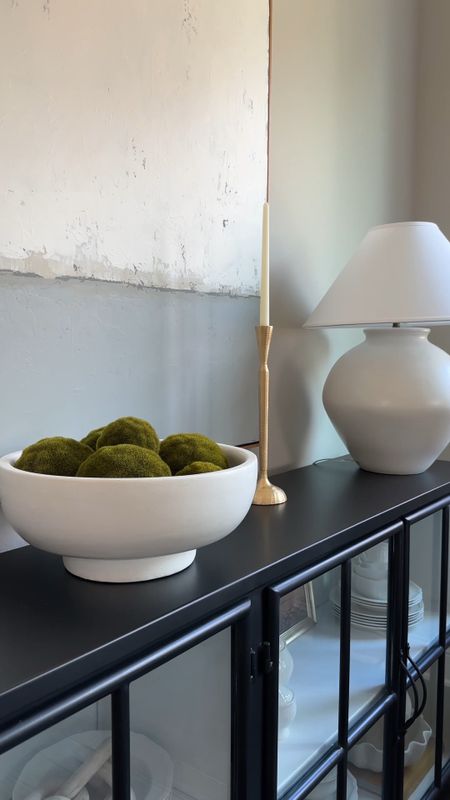 A close up of my dining room console with the gold taper candle holders, white statement lamps, pottery barn bowl, with green moss balls and neutral abstract art. 

#LTKFind #LTKstyletip #LTKhome