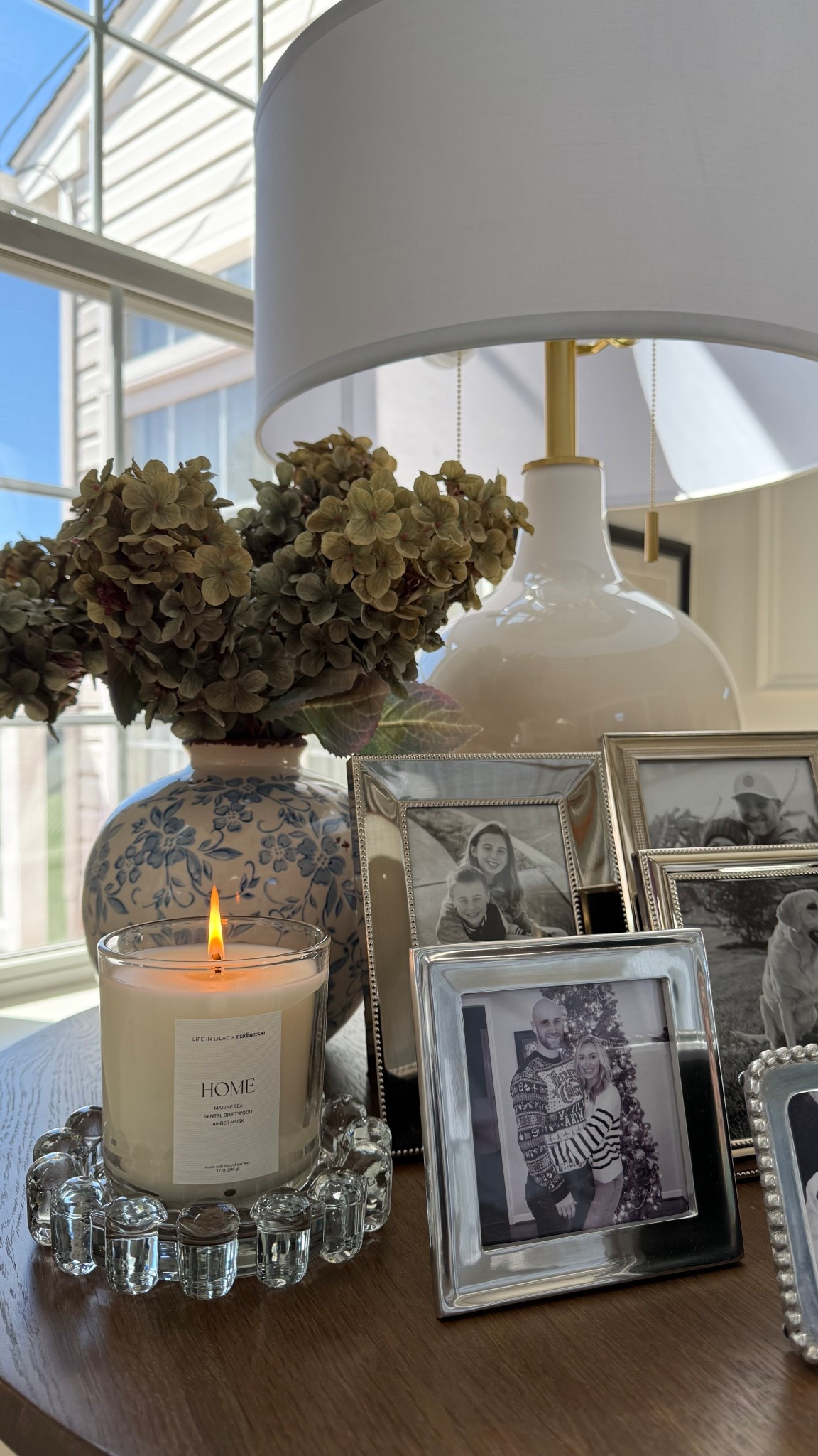 Cozy side table styling . Spring decor. Spring candle. Blue and white. Table lamp. Picture frames. Silver picture frames. 

#LTKSeasonal #LTKmomlife #LTKHome