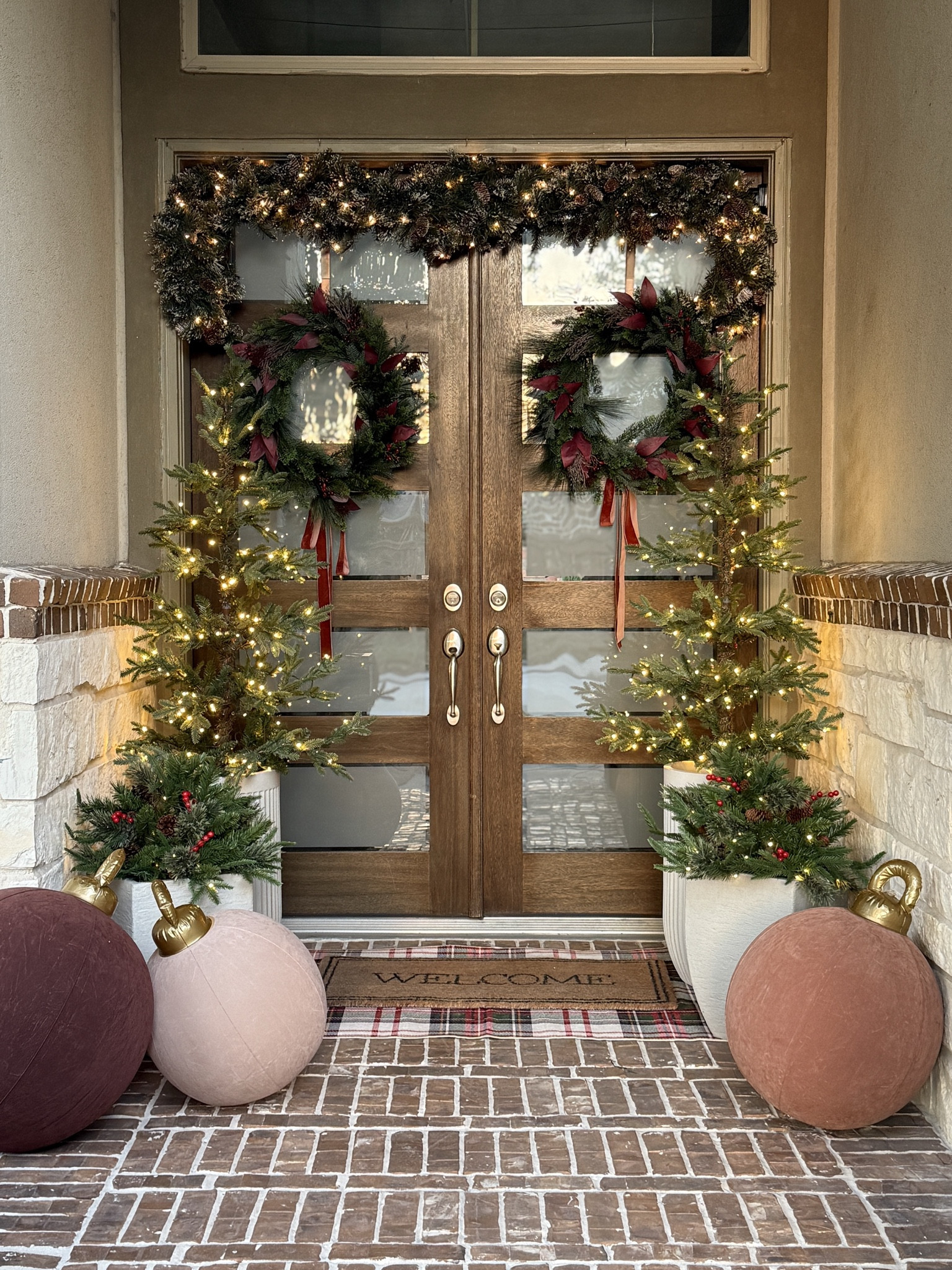 The front porch all dressed up for Christmas! Layered rugs, glowing trees, and classic wreaths with a touch of red! Christmas porch decor, front porch Christmas ideas, outdoor holiday decorations, pre-lit trees, Christmas wreath styling neutral Christmas decor elegant holiday porch giant ornaments classic Christmas 

#LTKHoliday #LTKSeasonal #LTKHome