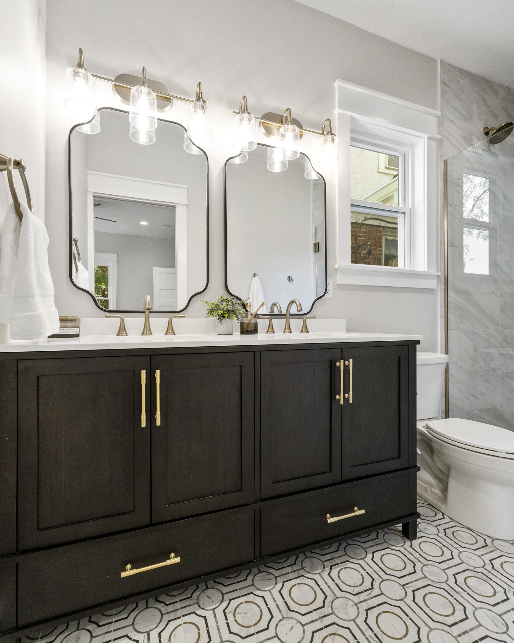 An elegant en-suite primary bath with a 60” black vanity and gold accents.  

#LTKHome