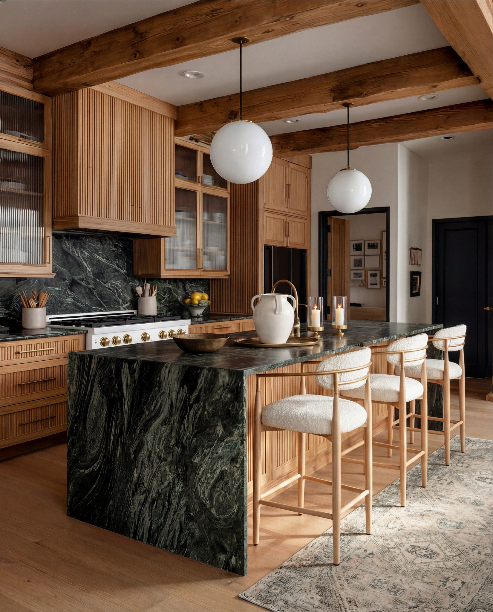 A warm modern kitchen grounded in natural textures and dramatic stone. The vertical slatted wood cabinetry brings soft dimension, perfectly paired with exposed ceiling beams that add depth and architectural charm. The real showstopper is the dark green marble—sweeping, organic veining wraps the island waterfall and backsplash for a bold, collected feel.

Light oak bar stools with boucle seats soften the rich materials, while the globe pendant lights bring a modern, sculptural glow over the island. A vintage-pattern runner warms the floor and ties every tone together, from the gold hardware to the creamy ceramics and brushed brass accents.

Shop the Look:
• Dark green marble waterfall island (forest + charcoal tones)
• Vertical slat wood kitchen cabinets (light natural oak)
• Boucle and oak modern counter stools
• White globe pendant lights (antique brass rod)
• Brass hardware + brass appliance knobs
• White gas range with brass details
• Textured ceramic pitcher + matching countertop décor
• Gold tray + candle set
• Dark wood bowl (centerpiece accent)
• Vintage-style runner (taupe, beige, soft charcoal pattern)
Black Friday

#LTKCyberWeek #LTKHome #LTKSaleAlert