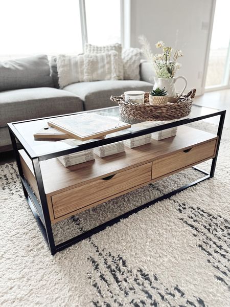 Coffee table on sale!!  Living room furniture along with cream textured throw pillows.  Wood and glass modern coffee table - tray filled with faux stems and candle.  Area rug is textured and has a modern linear design.  Modern style - home decor 

#LTKsalealert #LTKFind #LTKhome