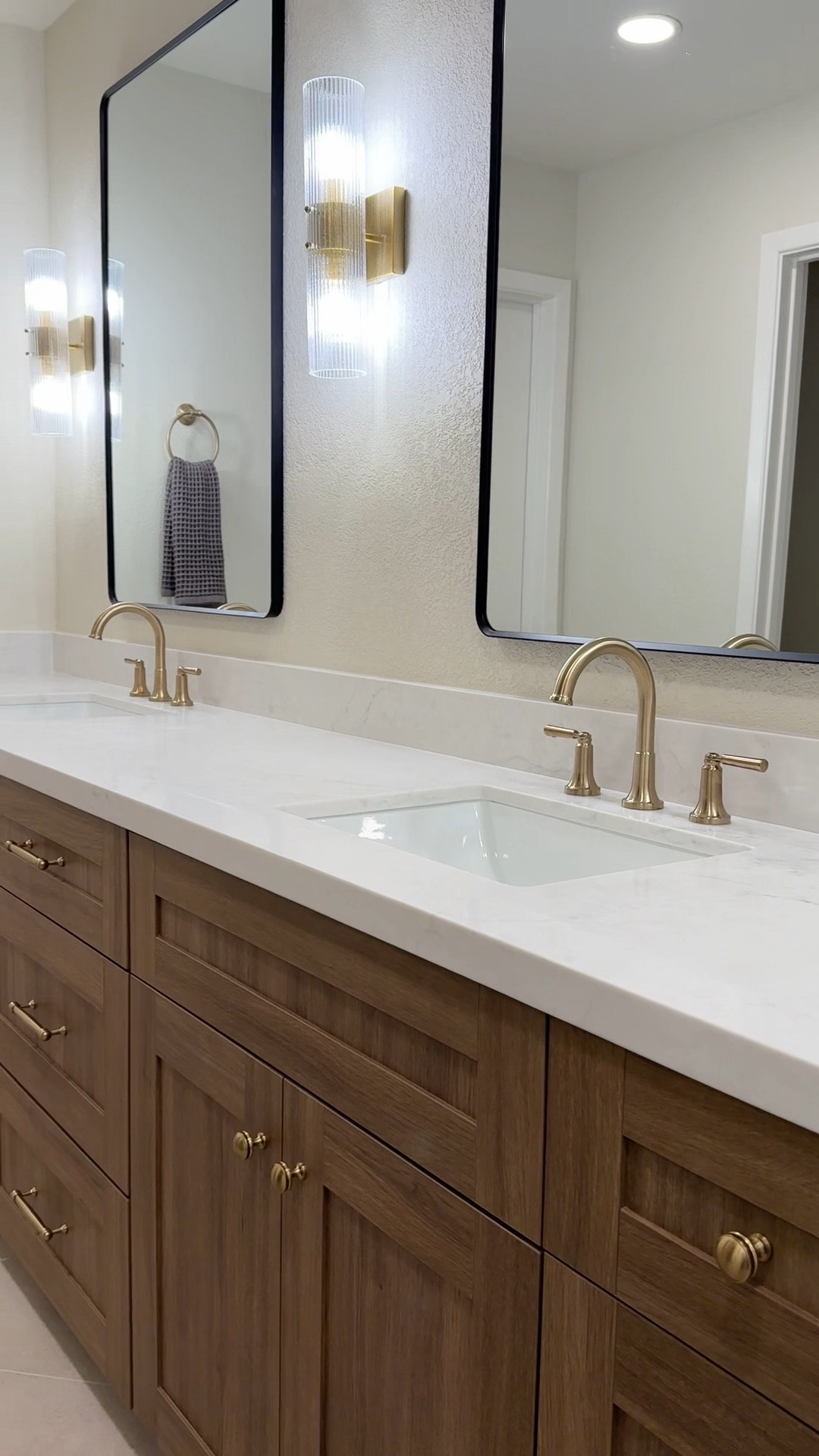 Primary bathroom🤩 I love the luxury feel of this bathroom with wood cabinets and earthy tones. Champagne bronze (gold) fixtures add warmth and luxury! Once this space is styled it will be all tied together! 
••
Sconces, gold sconce, sconce, bathroom sconce, chandelier, bathroom chandelier, bathroom lighting, semi flush mount light, free standing tub, freestanding tub, soaking tub, tub filler, sink faucet, champagne bronze, gold faucet, shower head, shower system, bathroom mirror, framed mirror, wood cabinets

#LTKHome