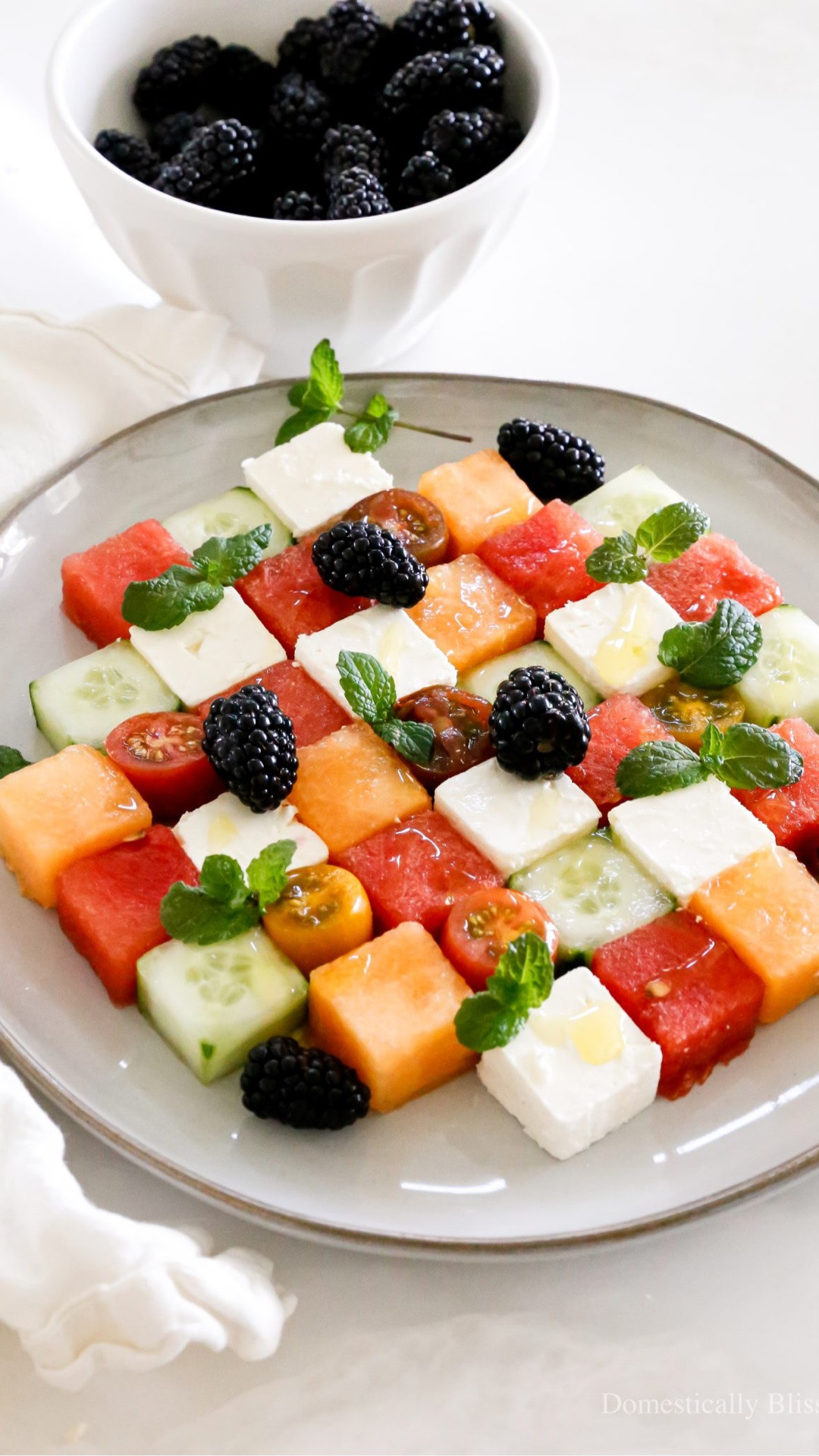 This Mosaic Fruit Salad is the perfect summer treat that is so fun to make!
I love a refreshing fruit salad, and this one is loaded with fresh, juicy summer flavors.
And to make it extra fun, I cut the watermelon, cantaloupe, cucumber, and feta into little squares.
This plate was pretty big, and we ended up enjoying the extras (the pieces I cut off) as a snack after making it, and then saved this delicious plate of summer fruit for the next day.
The three of us ate it for breakfast, and there was just enough left for little Roger Dale and me to eat what was left for lunch, too.
When I was a kid, we ate so much feta that I needed a break and went for over a decade without being a fan.
But taste buds are always changing (it’s why we should always try things again and again), and after eating this Mosaic Fruit Salad, I was shocked to find that I am once again a fan of feta!
What’s something you didn’t use to like eating but now love?

See details:
https://domesticallyblissful.com/mosaic-fruit-salad/

#LTKfoodie #LTKSeasonal #LTKvlog
