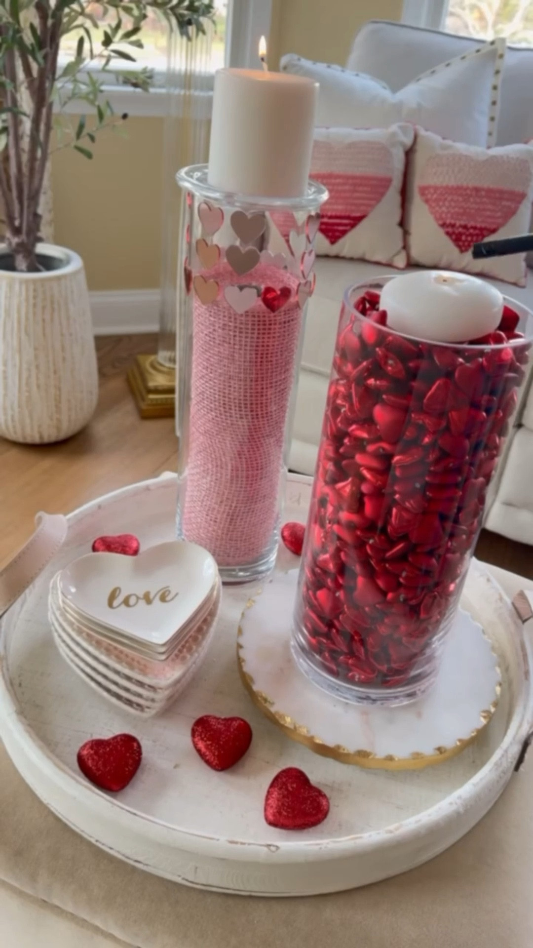Soft, romantic Valentine’s Day décor 🤍✨
I styled this cozy vignette using clear glass hurricane vases filled with pink mesh ribbon and metallic red hearts, finished with flameless candles for a warm glow. Layered on a neutral tray with heart accents and love-inspired dishes, it’s an easy, elegant way to add Valentine charm to a coffee table, console, or bedroom. Simple swaps, big impact—perfect for seasonal styling without overdoing it 💕

#LTKhome #LTKseasonal #LTKValentines #ValentinesDecor #HomeDecorInspo #SeasonalStyling #NeutralHome #RomanticDecor #CozyHome #HeartDecor #CoffeeTableStyling #DecorDetails #LoveIsInTheAir 
