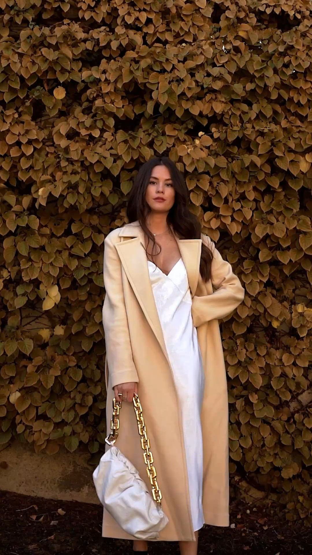 Chic fall outfit idea: pair a white satin maxi slip dress with a beige wool belted trench coat for an elegant, timeless fall look. Perfect for work, dinner, or weekend outings. 🍂 #FallOutfitIdeas #FallFashion #SatinSlipDress #TrenchCoatOutfit #NeutralStyle #LTKFallFashion
