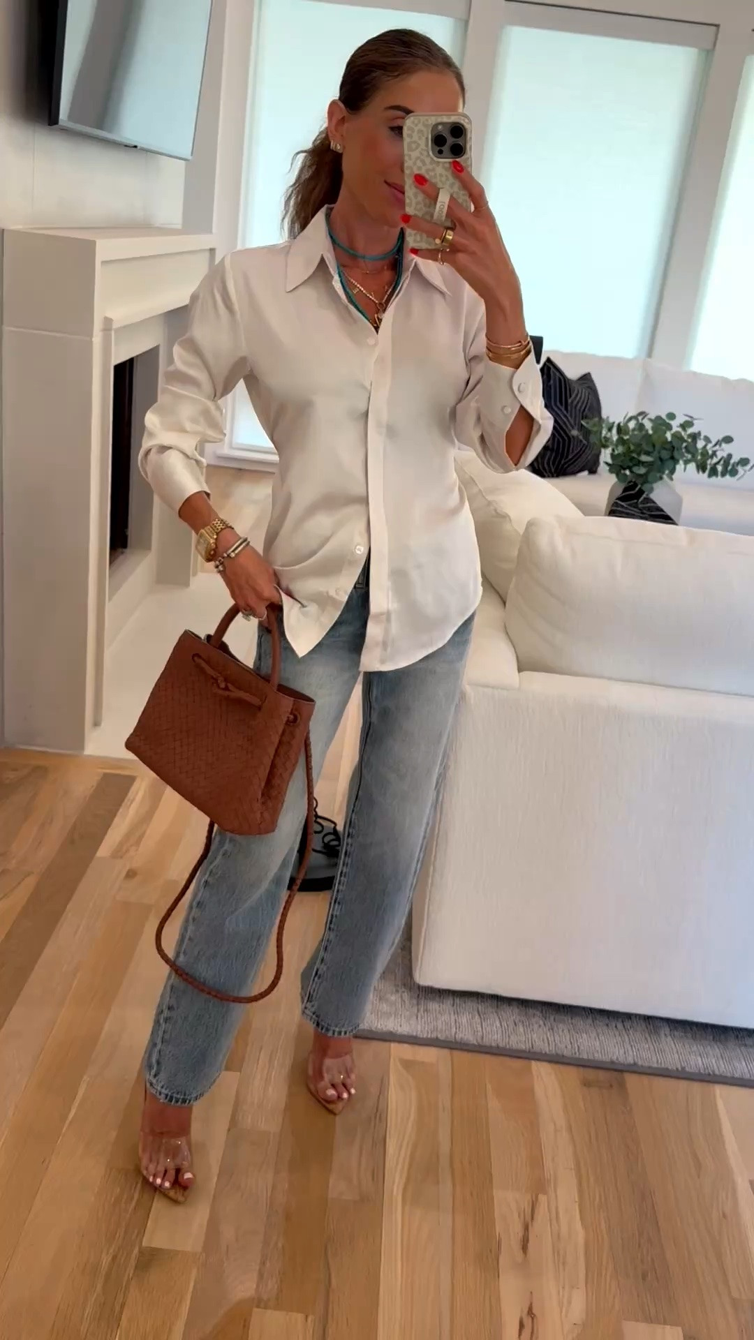 An easy fall outfit idea or date night outfit wearing this satin button down shirt in xxs with jeans and heels
