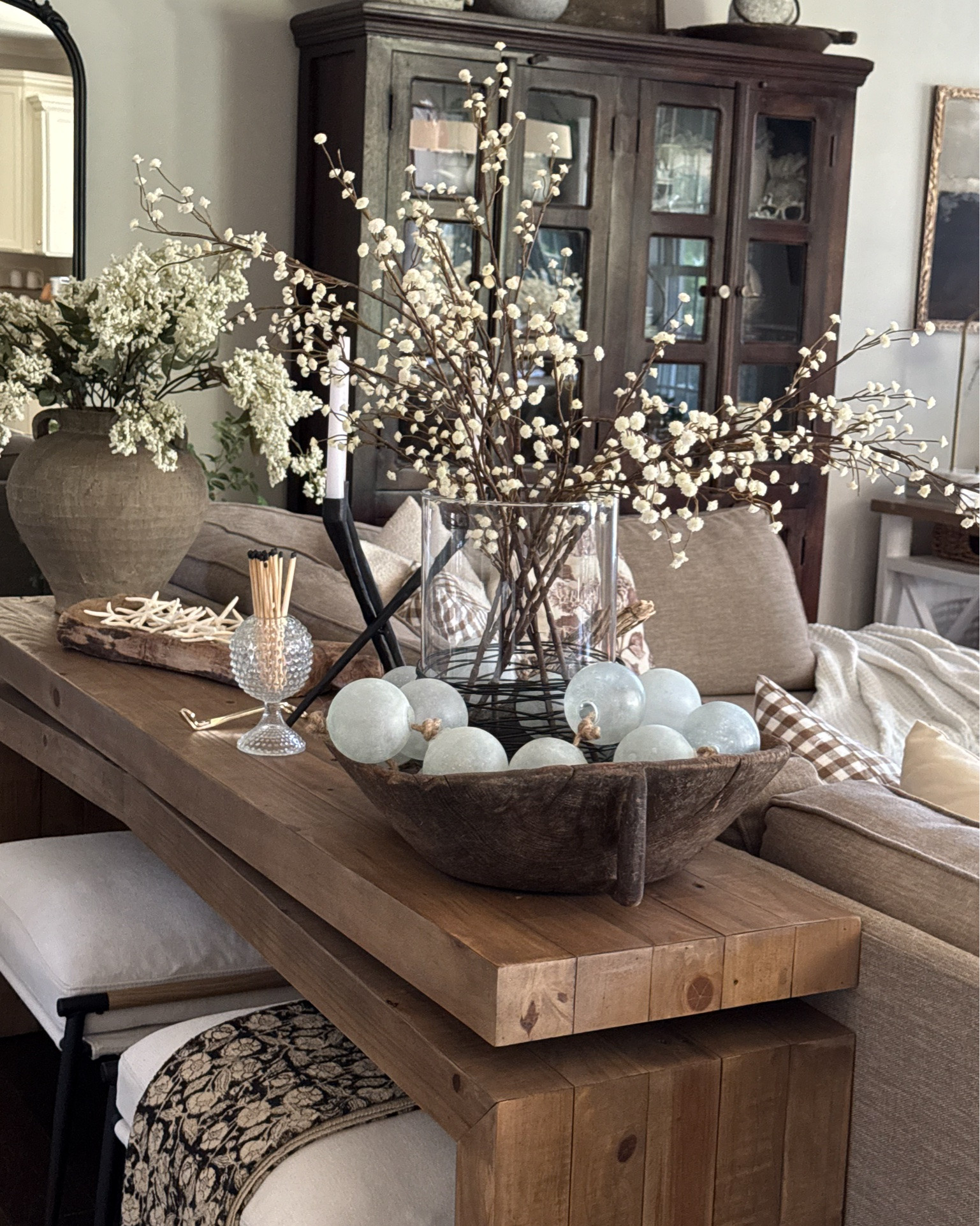 Summer Living Room with Coastal Touches💙🐚
Vintage and coastal style go together beautifully. I love layering my coastal decor with vintage finds during the summer months. I have found the most realistic baby’s breath. Best I’ve seen yet!!

Sea-glass garland, vintage wood bowl, vintage wood tray, glass cylinder, faux baby’s breath, vintage hobnail Ivy bowl, matches, console table, ottomans, floral throw blanket, starfish, candle pedestal, woven storage boxes, round coffee table, black candelabra, throw pillows, pillow inserts, floor lamp with woven shade, taupe vase, white berry stems, upholstered side chair

#LTKSeasonal #LTKstorytime #LTKHome