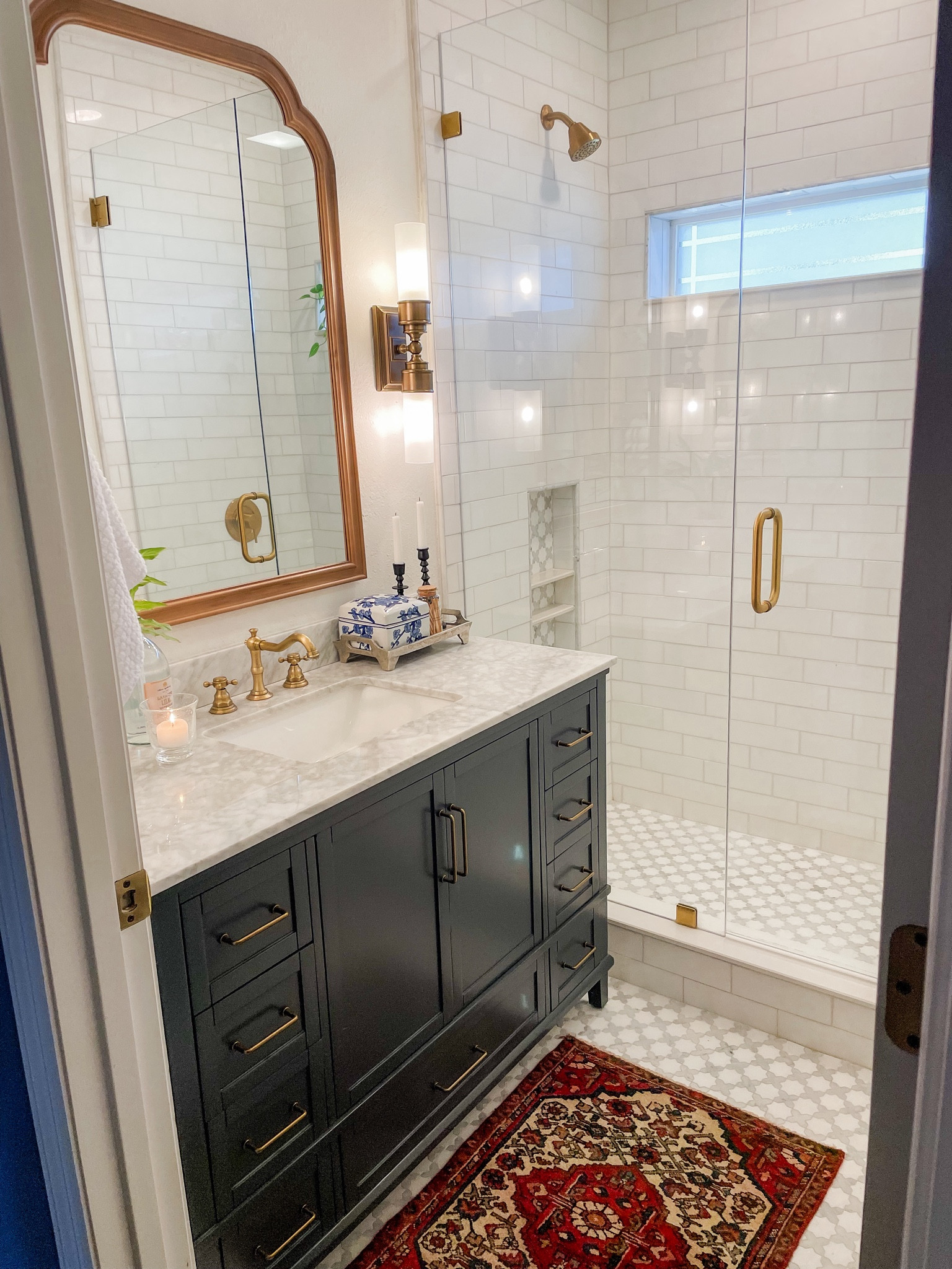 Bathroom remodel. Small bathroom, dark blue gray vanity, cross and star marble tile, glass shower, brass fixtures and open shelving. 

#LTKhome