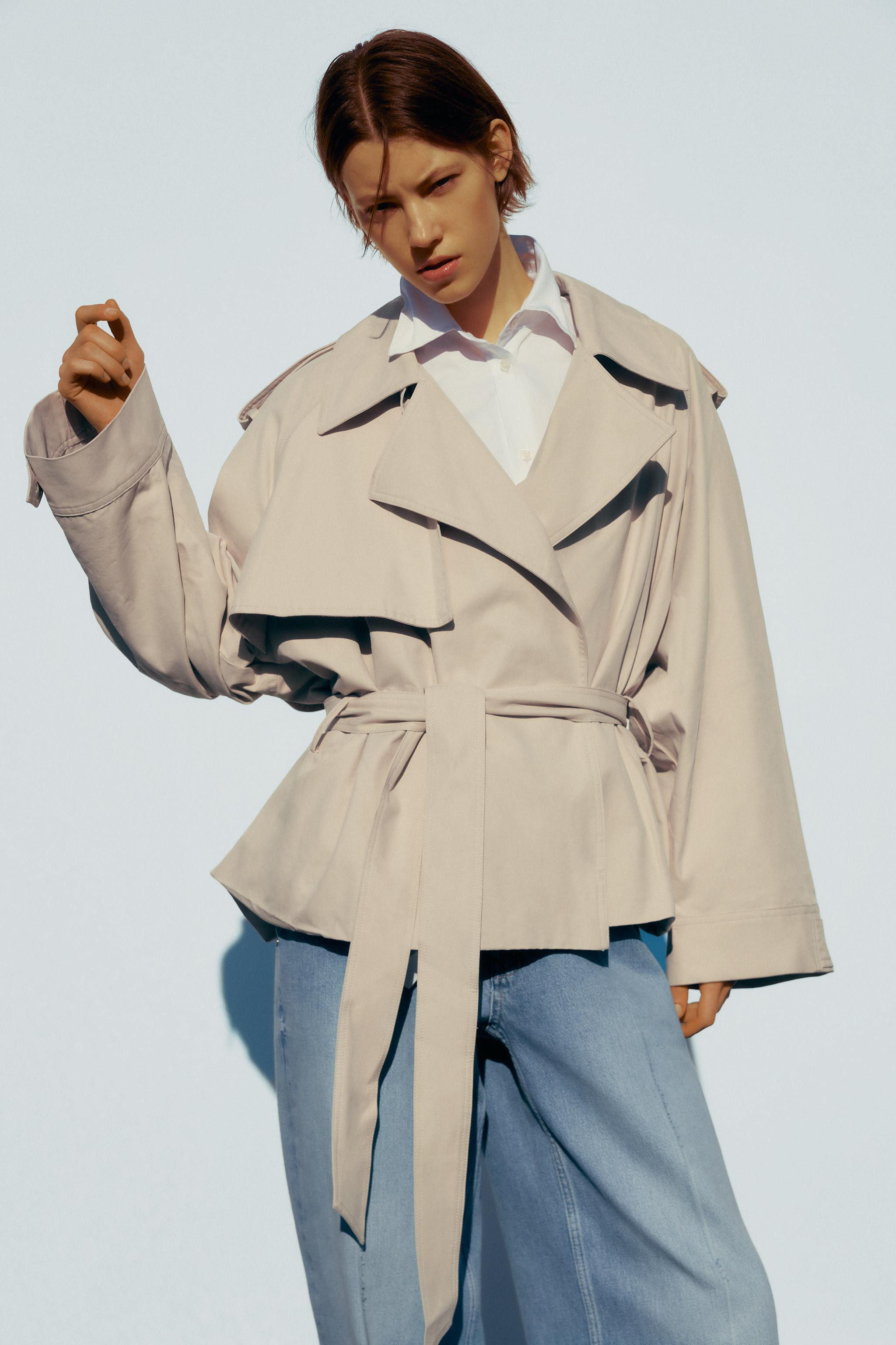 Short trench coat with lapel collar. Long sleeves with dropped shoulders and tabs. Matching linin... | Zara US