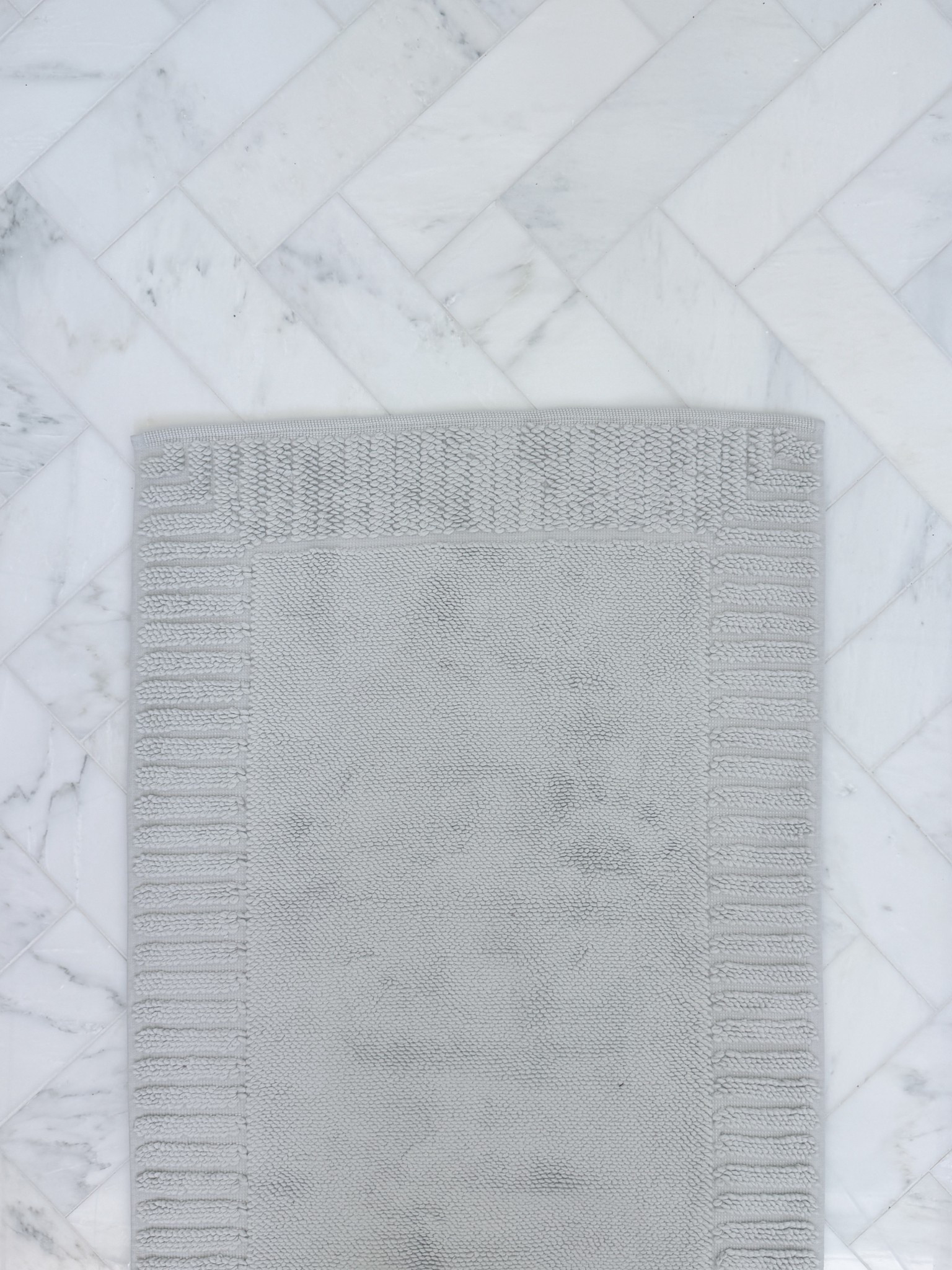 This bath mat is so soft! Super thick light gray bathroom rug is so absorbent & has the prettiest detail along the edge. It comes in multiple sizes & colors too! I love how the fog color coordinates so beautifully with the marble herringbone floor  

#LTKmorningroutine #LTKHome #LTKSaleAlert