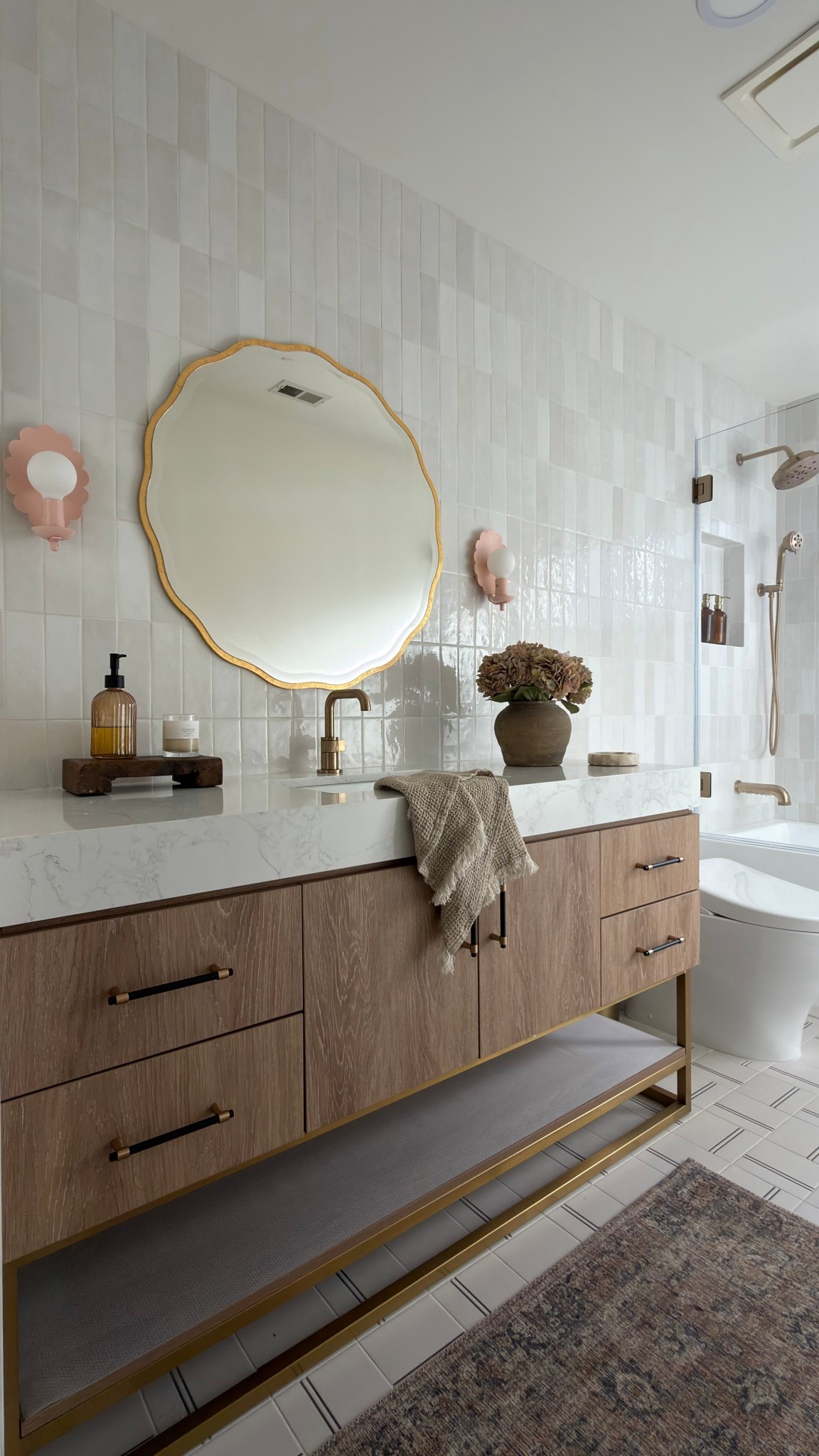 This bathroom was designed with so much thought and making it look high end on a budget. The handmade looking tile is a great price point and looks so much more expensive than it really is. This vanity looks so custom and saved our clients so much $$$$. Anytime you can buy a vanity with a countertop you’ll save thousands since you don’t have to buy a countertop plus pay for fabrication. Wayfair is always my go to for custom looking vanities and anything home decor related. Be sure to check it out! 

#ad #wayfair @wayfair #wayfairpartner

 Wood vanity oval capsule, mirror, rectangle, mirror, medicine cabinet, brass faucets, brass hardware, shower system, white soaking tub bra, sconces, bubble chandelier, bathroom, accessories, white tile, gray tile marble tile sink rug runner