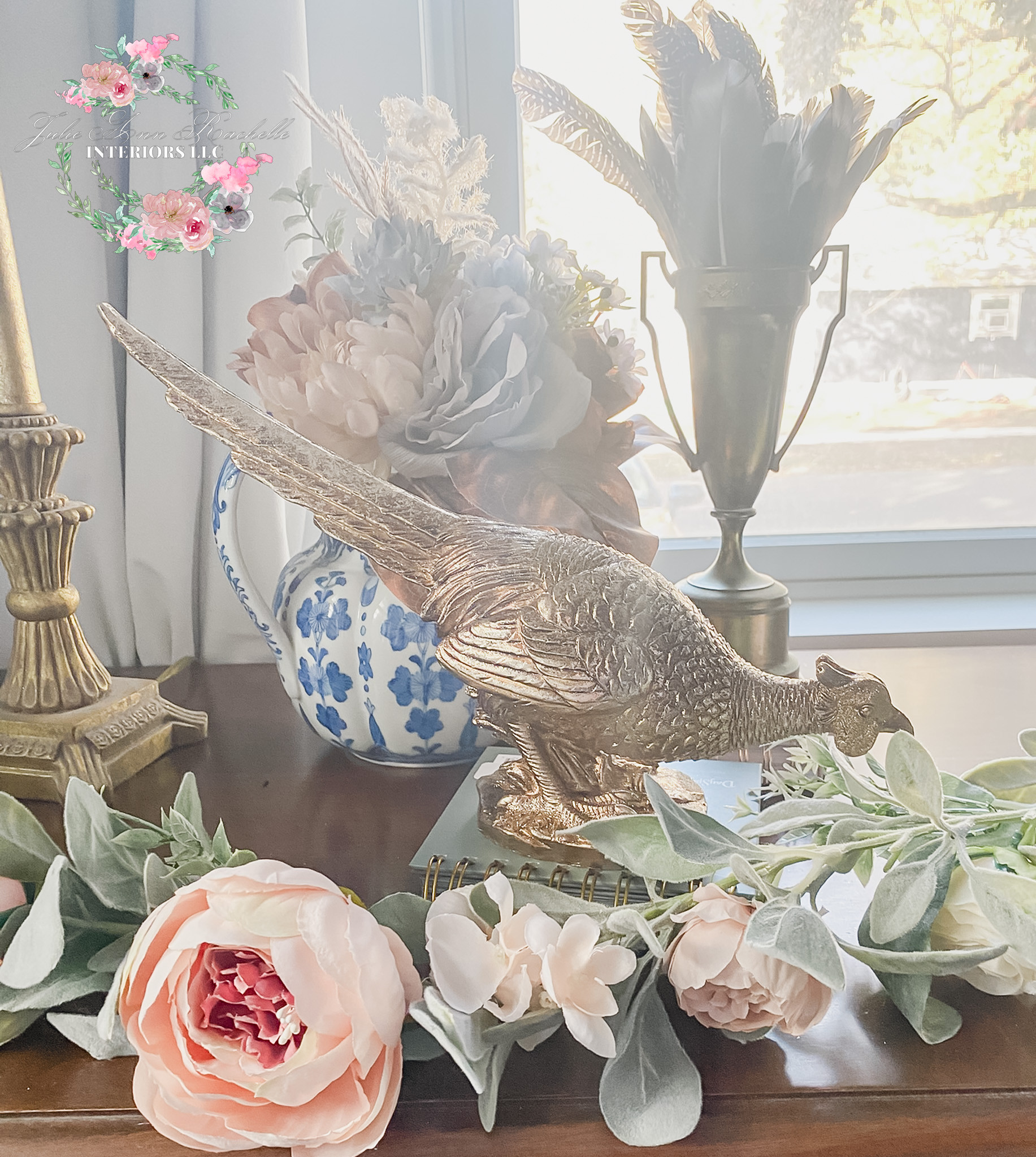Bring on cozy harvest season with my blue-and-brass vignette—easy to recreate on a mantel, console, or dining buffet. I start with a 𝐛𝐫𝐚𝐬𝐬 𝐩𝐡𝐞𝐚𝐬𝐚𝐧𝐭 as the focal point. The medium size adds warmth and a little movement without blocking sightlines at dinner. To soften the metals, I layer a 𝐟𝐚𝐮𝐱 𝐩𝐞𝐨𝐧𝐲 + 𝐞𝐮𝐜𝐚𝐥𝐲𝐩𝐭𝐮𝐬 𝐠𝐚𝐫𝐥𝐚𝐧𝐝 in soft green with blush/ivory blooms. It reads full on its own; for evening, tuck in a strand of micro LEDs and you’re done.⁣....
⁣
For height (and that “finished” look), I bundle 𝐩𝐡𝐞𝐚𝐬𝐚𝐧𝐭 𝐟𝐞𝐚𝐭𝐡𝐞𝐫𝐬 in an 𝐚𝐧𝐭𝐢𝐪𝐮𝐞 𝐛𝐫𝐚𝐬𝐬 𝐮𝐫𝐧 𝐨𝐫 𝐭𝐫𝐨𝐩𝐡𝐲. The narrow mouth keeps stems upright so you don’t need floral foam. A 𝐛𝐥𝐮𝐞-𝐚𝐧𝐝-𝐰𝐡𝐢𝐭𝐞 𝐜𝐡𝐢𝐧𝐨𝐢𝐬𝐞𝐫𝐢𝐞 𝐩𝐢𝐭𝐜𝐡𝐞𝐫 rounds out the palette and bridges summer to fall—classic, collected, and perfect for October through Thanksgiving.⁣...
⁣
**𝐇𝐨𝐰 𝐭𝐨 𝐬𝐭𝐲𝐥𝐞 𝐢𝐧 𝐦𝐢𝐧𝐮𝐭𝐞𝐬**⁣
⁣
1. Place your brass pheasant slightly off-center.⁣
2. Drape garland in a loose “S” curve—let a few leaves spill naturally.⁣
3. Add height with 7–12 feather stems in a footed urn.⁣
4. Finish with one blue-and-white piece to echo the brass and greenery.⁣
   𝐃𝐞𝐬𝐢𝐠𝐧𝐞𝐫 𝐭𝐢𝐩: Use the rule of thirds—one hero (pheasant), one tall element (feathers), one supporting piece (vase/garland).⁣.....
⁣
**𝗪𝐡𝐞𝐫𝐞 𝐢𝐭 𝐰𝐨𝐫𝐤𝐬:** entry console, living-room mantel, sideboard, or a Thanksgiving tablescape (keep the pheasant low so guests can chat across the table).⁣...
⁣
**Tap to shop the exact or similar pieces:**⁣
• Brass Pheasant Figurine (medium)⁣
• Faux Peony & Eucalyptus Garland (approx. 6 ft)⁣
• Pheasant Feather Stems (bundle)⁣
• Antique Brass Urn Vase (medium)⁣
• Blue-and-White Chinoiserie Vase/Jar (botanical motif)⁣
⁣
Follow @𝐣𝐮𝐥𝐢𝐞_𝐚𝐧𝐧_𝐫𝐚𝐜𝐡𝐞𝐥𝐥𝐞 for more fall styling, Thanksgiving tables, and easy porch refresh ideas. Save this for your weekend decor reset!⁣
#fallhome #harvestdecor #thanksgivingtable #manteldecor #blueandwhite #traditionalhome #cozyvibes #tablescape 

 

#LTKHoliday #LTKHome #LTKFindsUnder50