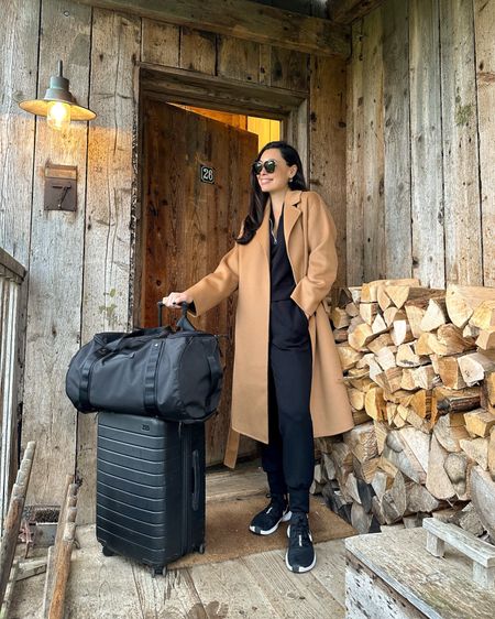 Kat Jamieson wears a camel coat and jogger set to travel in. Travel outfit, comfy cozy style, athleisure, suitcase, luggage, sneakers. 

#LTKfitness #LTKSeasonal #LTKtravel