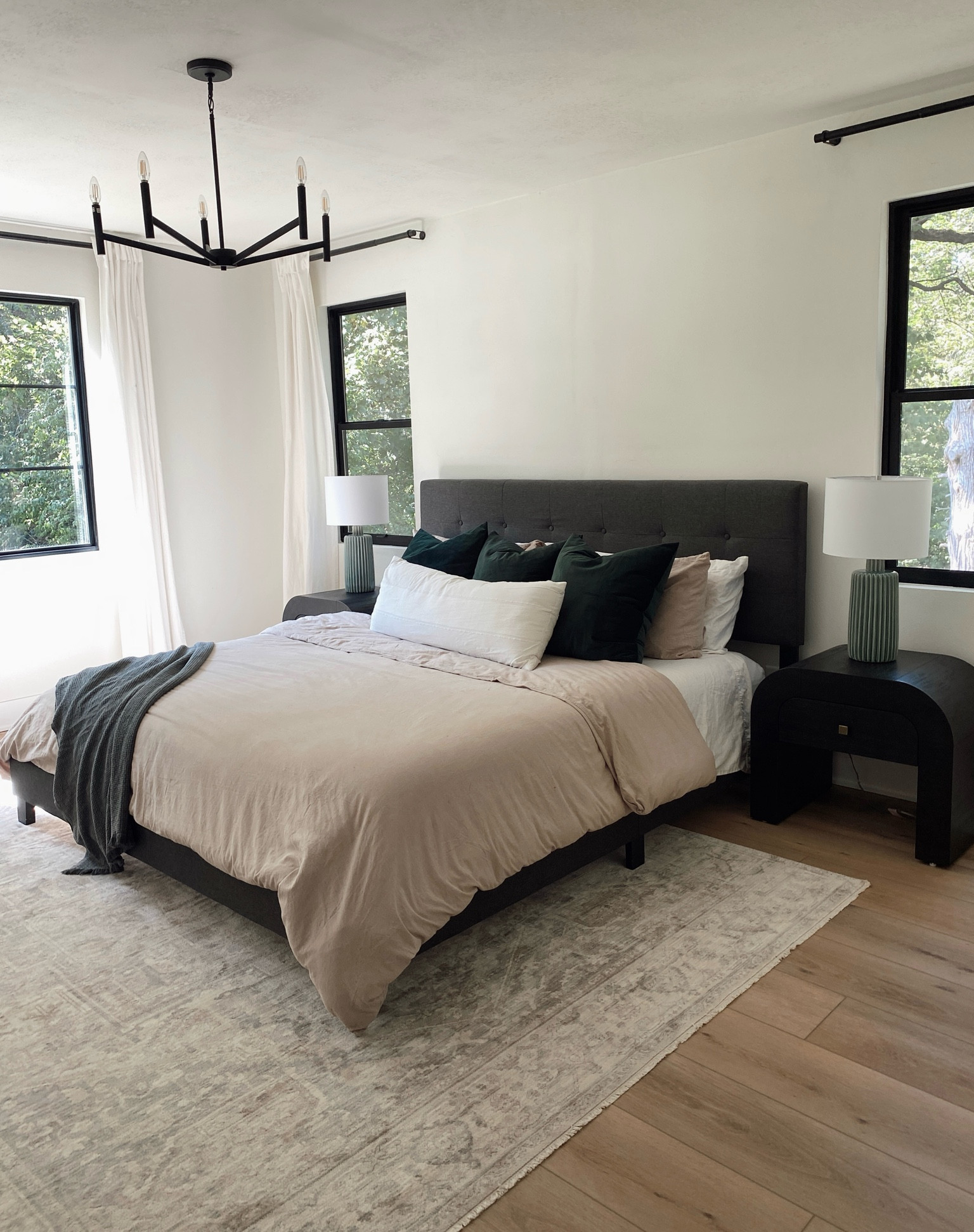 Our primary bedroom remodel! We went with a modern minimal style with some transitional elements to keep it cozy. Everything linked from the neutral area rug, black arched nightstands, green ceramic lamps, bedding, curtains and black chandelier. 

#LTKFindsUnder100 #LTKHome