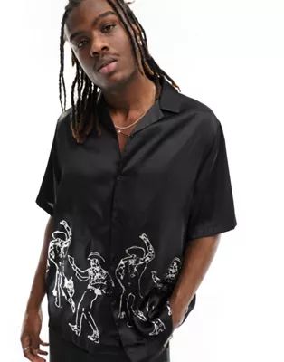 ASOS DESIGN relaxed camp collar satin shirt in black with foil cowboy print | ASOS (Global)