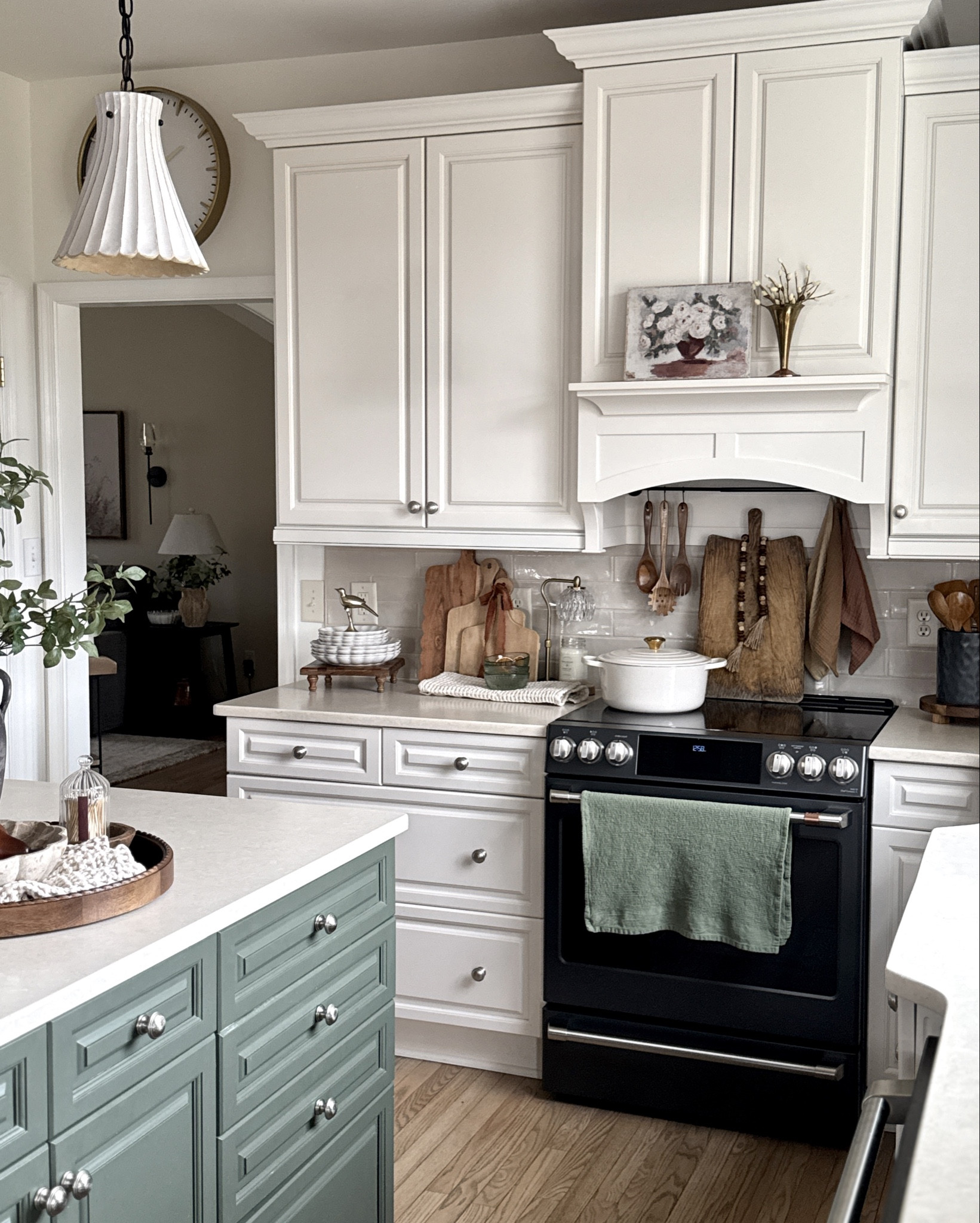 Warm up your kitchen with dark green stems and lots of warm wood tones. Much of what you see here is linked: bread boards, cutting boards, wood riser, wooden pears, pretty glass match holder, gold bird figurine, black vase, green stems, utensil holder, wooden utensils and tray back in stock, waffle towels, scalloped white dishes, green glass stacking bowls, candle warmer, candles, vases, the beautiful plum stems are back in stock, pendant lights. I also used a magnetic curtain rod to the back of our custom hood to hang pretties so we didn’t have to drill holes into the hood. Works excellent if your hood is metal in the back like ours. Rod linked here. My favorite Le Creuset braiser! 

#LTKFindsUnder50 #LTKHome