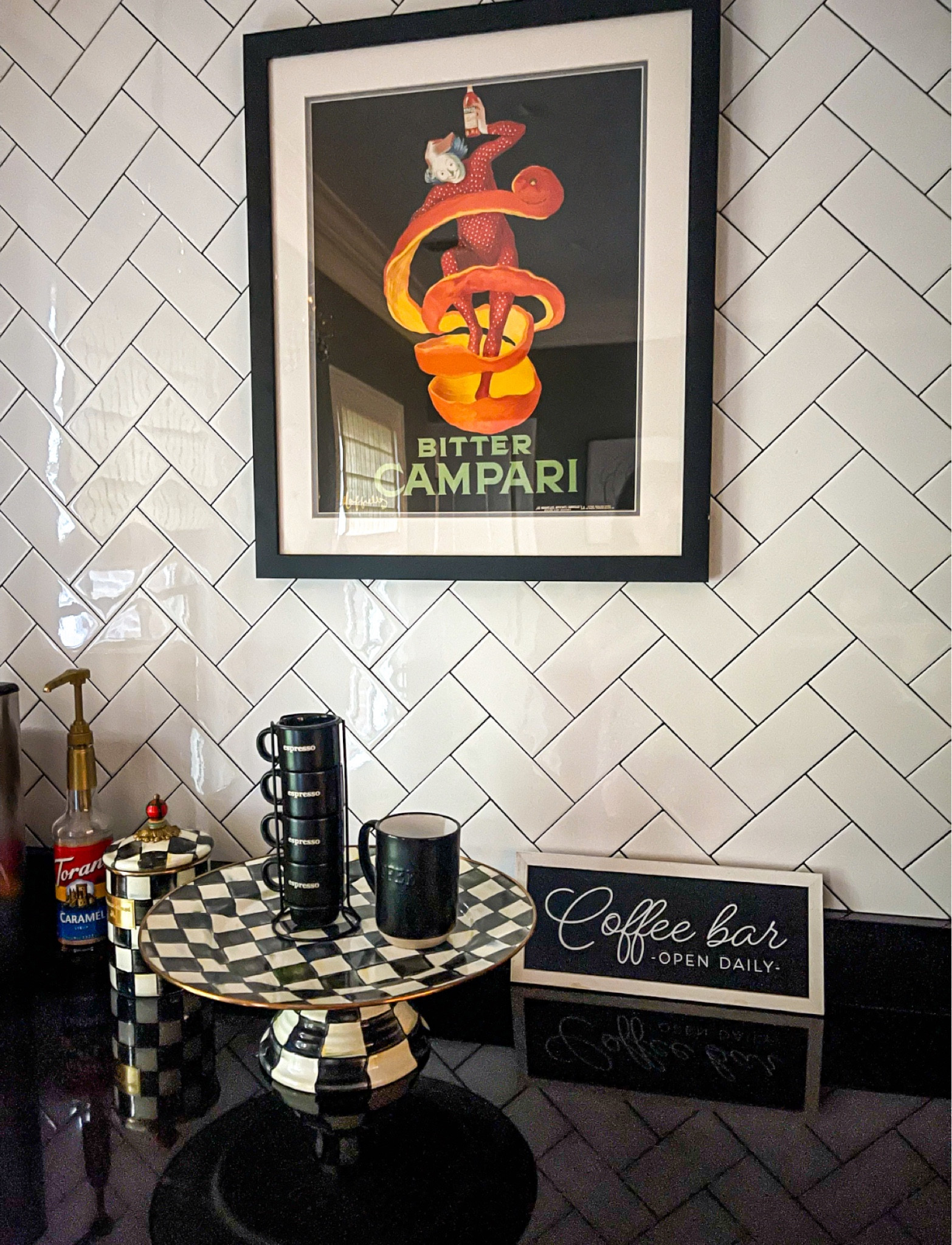 I love my black and white checkered coffee bar. My black marble kitchen coutertops accented with the gold black and white checkered sugar jar and serving platter at a dash of elegance. I use the Cuisinart Coffee Makerfor the perfect cup (or 2) every morning. I take my coffee in my ceramic black "coffee" mug with a few pumps of Torani caramel syrup and almond (or oat milk). I love how these espresso cups stack in their holder. The "Bitter Campari" artwork adds a little bit of flair and color. Coffee bar, coffee maker, coffee pot, espresso morning routine, caramel coffee, coffe mug, checkered kitchen, black kitchen, black and white kitchen, white subway tiles, Mackenzie-Childs courtly check, tray, espresso cups

#LTKfindsunder50 #LTKfindsunder100 #LTKhome