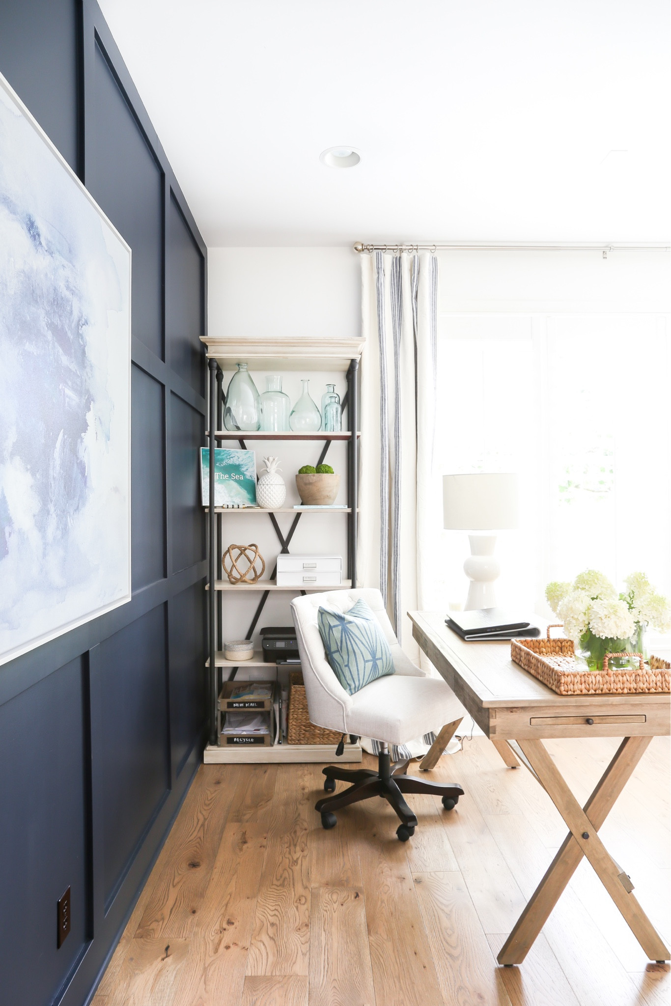 Our home office decor includes a natural wood desk, white table lamp, blue and white striped curtains, an off-white upholstered chair, decorative pillow and a woven basket. Items on the bookcase include a ceramic pineapple, white storage drawers and several glass vases. 

simple decor, office, home office, simple design, accent wall, coastal design, amazon home décor, amazon lamps, pottery barn office, world market décor, world market office, home office desk, office chair, amazon finds, container store, world market finds #ltkfamily #ltksalealert 

#LTKSeasonal #LTKunder50 #LTKunder100 #LTKhome #LTKstyletip #LTKhome #LTKunder100 #LTKsalealert