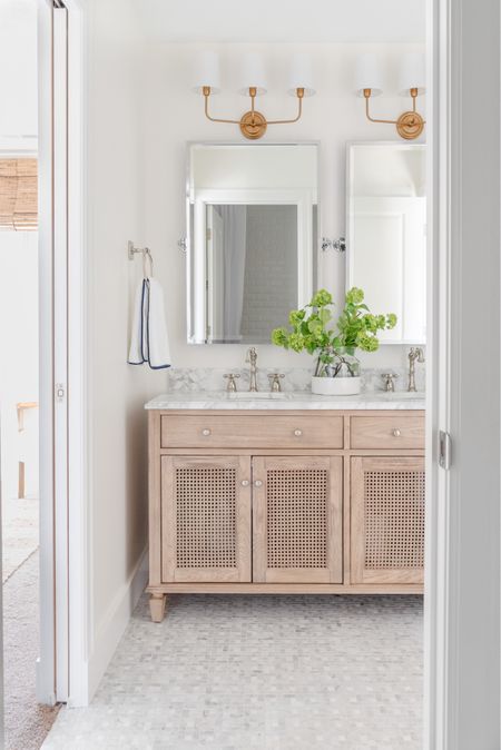 Our renovated guest bathroom in our last house includes a beautiful polished nickel faucet, a double sink cane vanity with marble top, a silver pivot wall mirror, a paint dipped vase with faux greenery, silver bathroom hardware, white hand towels with a navy blue border and brass sconce lights. Other items not shown include classic white subway tile, a white shower curtain and a gold star light flush mount. 

bathroom inspo, bathroom cabinet, bathroom decorating, bathroom countertop, bathroom hand towels, bathroom mirror, amazon home décor, amazon bathroom accessories, pottery barn vanity, lowes tile, serena and lily bathroom, serenaandlily vase, pb home, pottery barn mirrors, bathroom vanities, bathroom hardware, bathroom mirrors, bathroom accessories set, coastal decorating, coastal design, coastal inspiration             

#LTKfindsunder50 #LTKfindsunder100 #LTKSeasonal #LTKhome #LTKsalealert #LTKstyletip #LTKstyletip #LTKfindsunder100 #LTKhome #LTKSeasonal #LTKsalealert #LTKsalealert #LTKhome #LTKSeasonal #LTKsalealert #LTKhome #LTKSeasonal