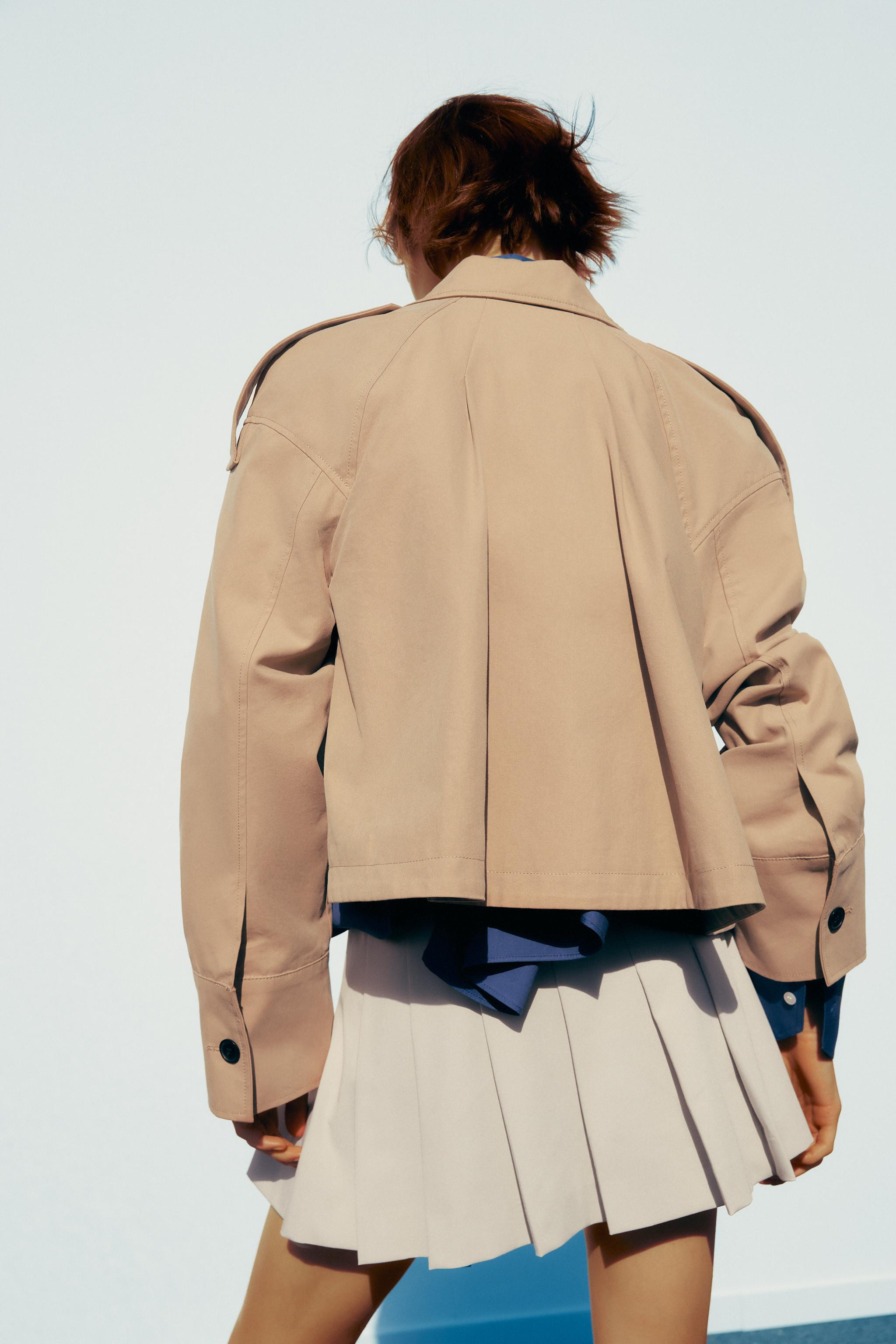 Short trench coat with a lapel collar and long sleeves with shoulder tabs and cuffs. Front pocket... | Zara UK