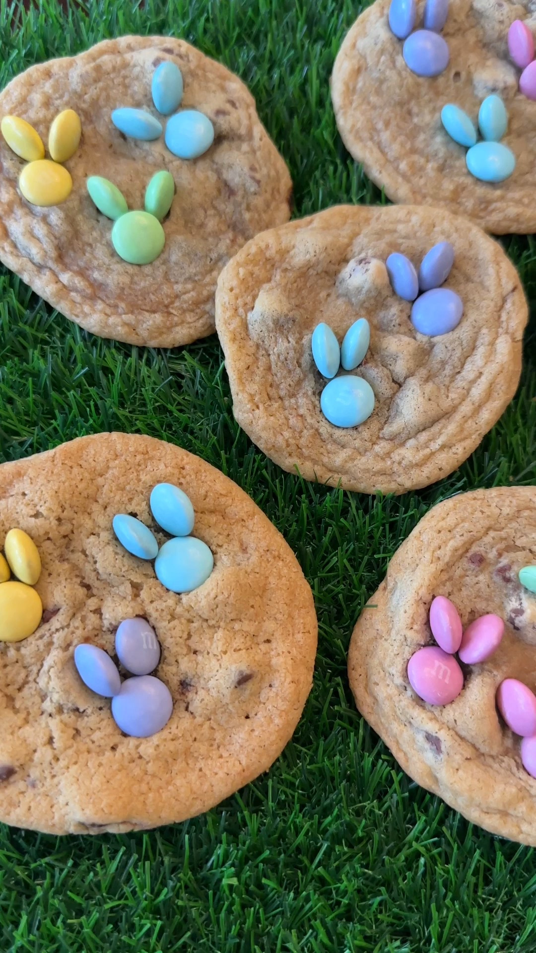 Bunny Cookies 

Here's what you'll need:
2 ¼ cups all-purpose flour
1 tsp baking soda
1 tsp salt
1 cup (2 sticks)  and 1 tbsp butter, softened
¾ cup granulated sugar
¾ packed, dark brown sugar
1 tsp vanilla extract
2 large eggs
2 cups Toll House semi-sweet chocolate morsels
1 package Pastel colored m&ms for the bunnies
 
Here's how you make them:
Preheat oven to 350°
Combine flour, baking soda and salt into a bowl.
In a mixer beat butter, sugar and brown sugar until pale and fluffy (about 7 minutes).
Add in vanilla and one egg at a time, beating well after each egg.
Slowly add in flour, until all combined.
Stir in chocolate chips
Use a cookie dough scoop to drop dough onto an ungreased and air bake cookie sheet.
Bake for 9-11 minutes, until just golden brown.
*While cooking - separate M&Ms by color, if you want each bunny one color. 
Straight from the oven, press the M&Ms into the cookie to create a face and ears as shown in the video. 
Let rest on cookie sheet for 3 minutes, then transfer to a cookie rack to cool.
Store in an air-tight container for up to 5 days.
 
Tips:
The cookie sheet makes a difference. Use an Air Bake sheet! I linked the one I use in my bio.
Cream the butter and sugar really well, I mean, turn the mixer on and walk away for 6 minutes. Trust me! 