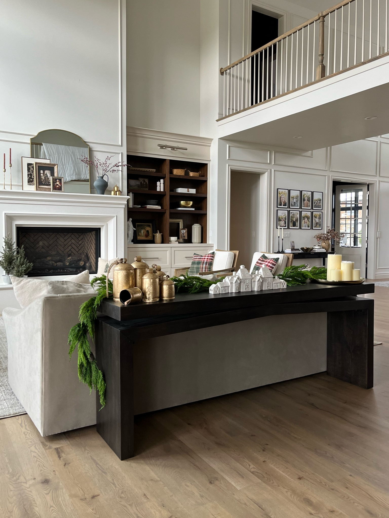 Holiday decor from Wayfair: brass bells, cedar garland, Christmas village with LED lights, pillar candles from Creative Co-Op, gold tray, all on the prettiest console table.

#LTKHoliday #LTKHome #LTKSeasonal