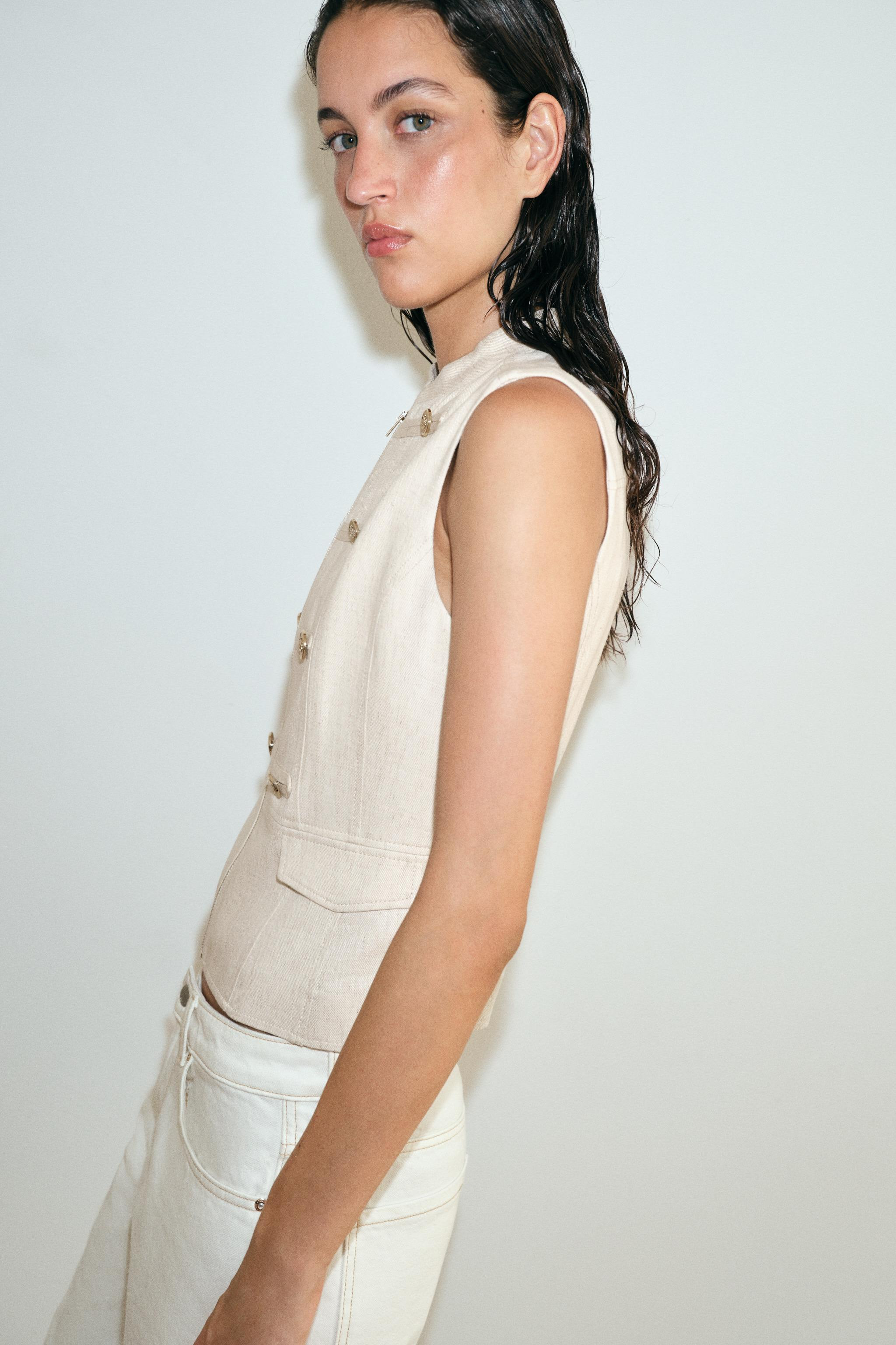 Round neck sleeveless vest. Features faux button detail and faux front flap pockets. Front zip cl... | Zara US