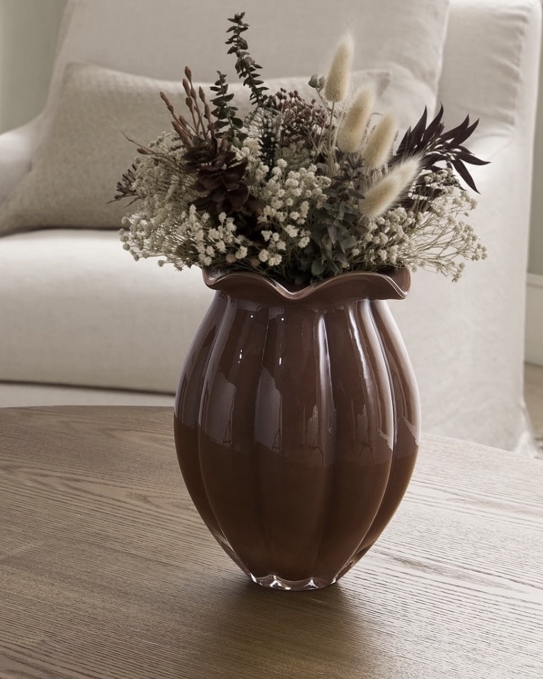 Decorative glass flower vase
	•	Softly fluted shape with brown milky glass finish
	•	Elegant decorative accent for shelves, consoles, and tabletops
	•	Smooth glass construction with glossy finish
	•	Perfect for displaying fresh florals, dried stems, or decorative branches
	•	Versatile accent for living rooms, bedrooms, entryways, and more