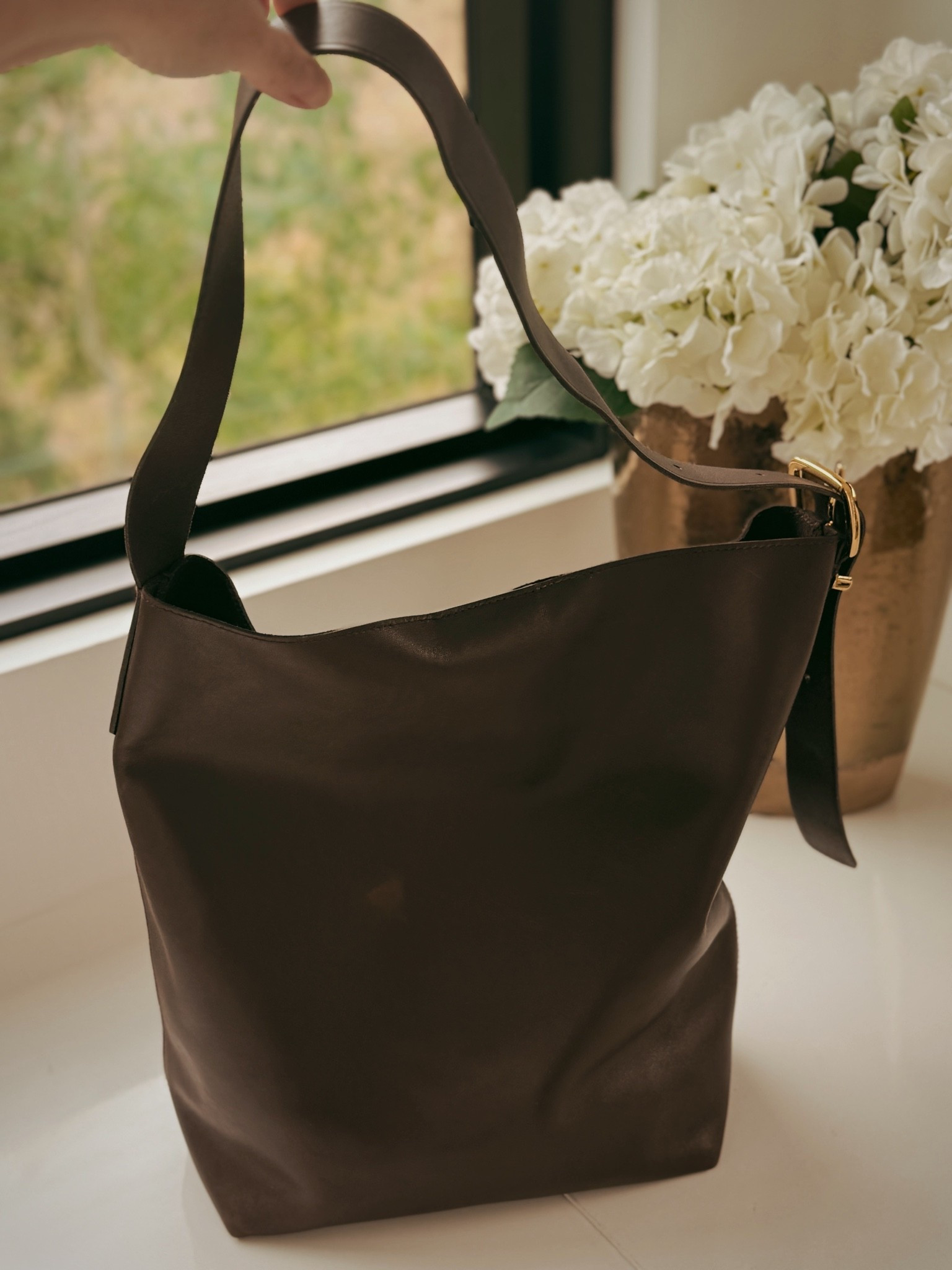 A dark chocolate leather tote is one of those wardrobe investments that pays for itself in wears. 

This Madewell Shopper Tote has a structured bucket silhouette, wide flat leather straps, and a gold buckle detail that keeps it from feeling too casual. Roomy enough to carry everything, polished enough to take anywhere.

#LTKootd #LTKgrwm #LTKOver40