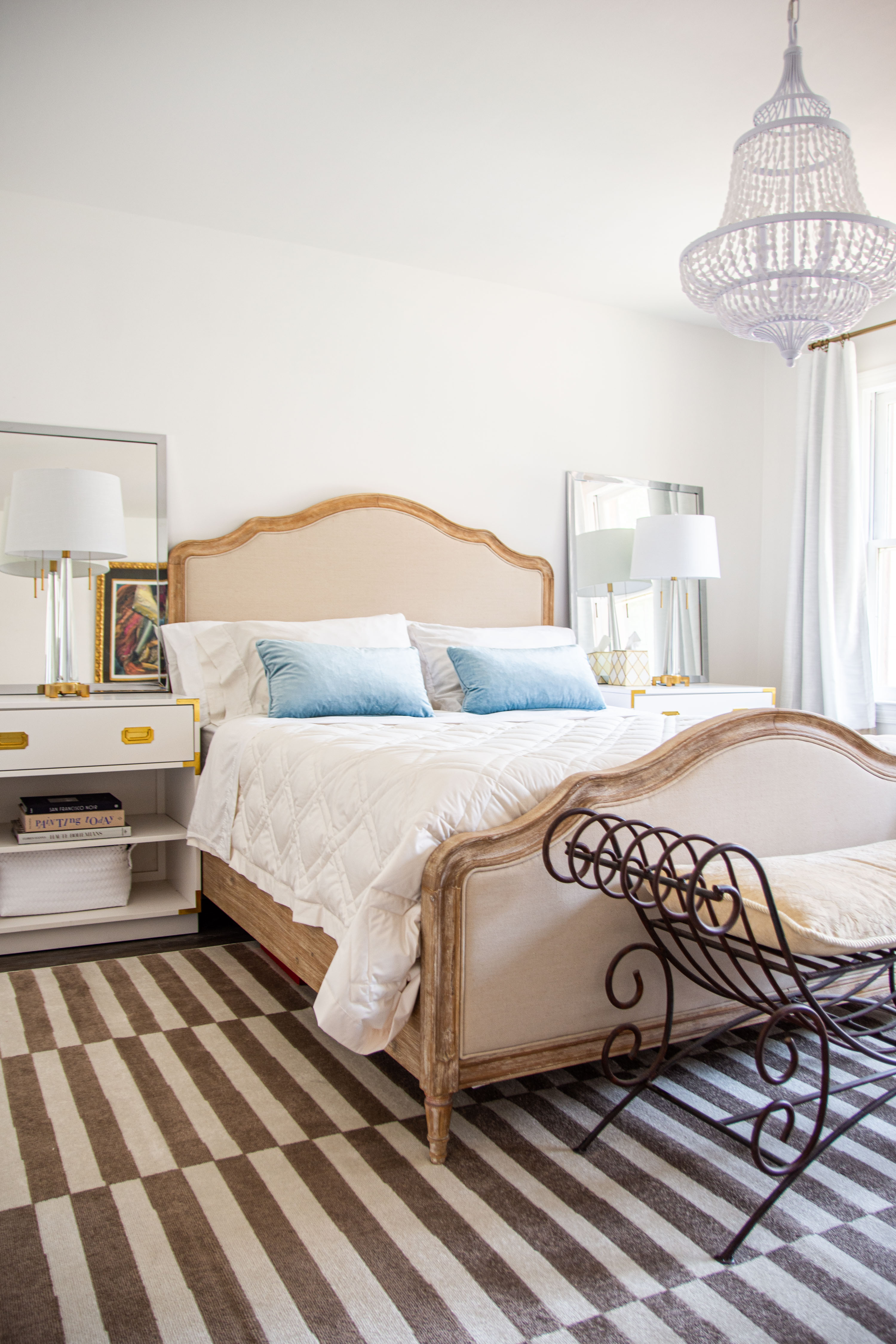 Blue and white bedroom design with French style upholstered Queen bedframe, white nightstands, crystal table lamps, white beaded chandelier, and brown and cream striped area rug  

 

#LTKHome #LTKStyleTip