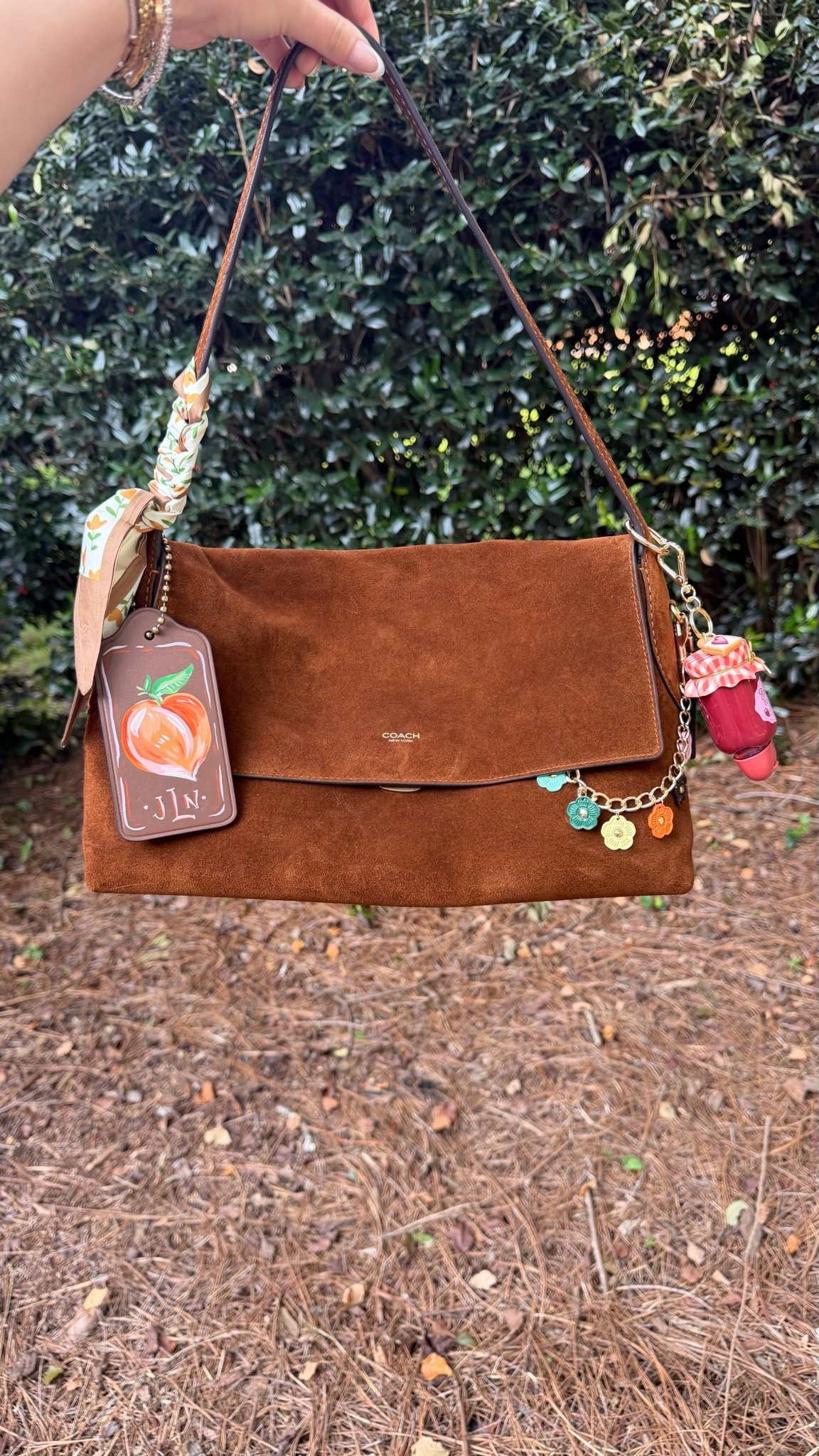 Bag of the day 🤎

Coach Chelsea 36 in suede
Custom large coach tag painted by Katherine Boggs 
Flower chain
Bath and body works hand sanitizer holder charm