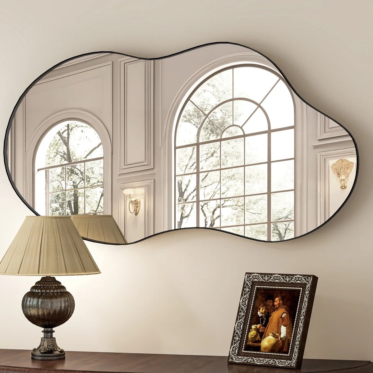 This asymmetrical wall mirror from Wayfair is such a fun statement piece for an entryway, bedroom, or above a console table. I love the organic wavy shape and slim black metal frame, especially styled with a pleated-shade table lamp and dark wood console.

#LTKHome #LTKSaleAlert