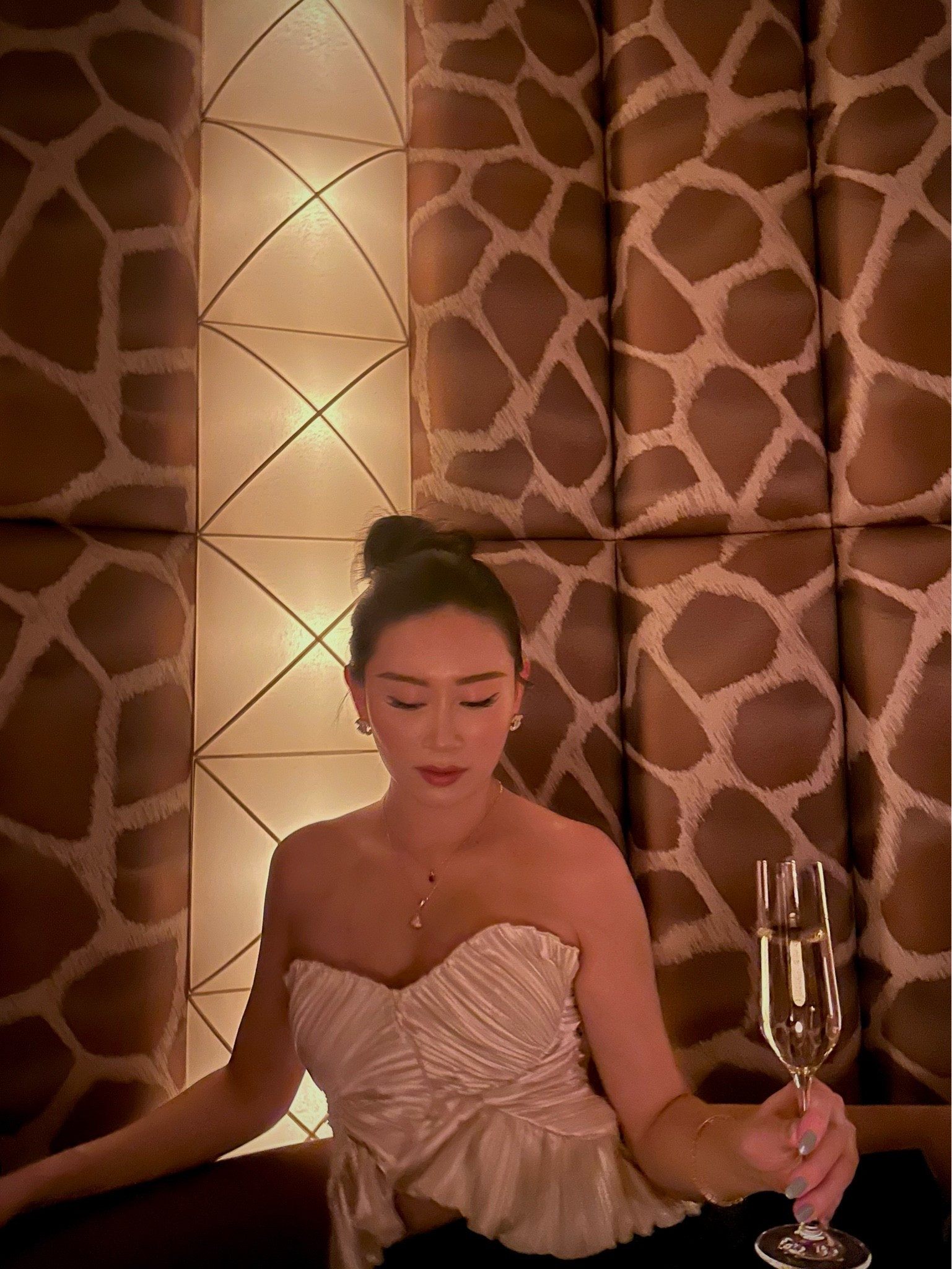 a champagne ruched satin strapless corset top with a sweetheart neckline and a flared peplum hem, styled with delicate gold jewelry and a sleek low bun. the structured boning and ruched satin give it a built-in hourglass shape that dresses up instantly for night. perfect for date nights, cocktail bars, birthday dinners, and going-out evenings. shop this look linked above.