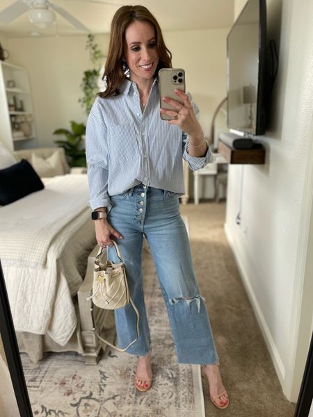 A dressy take on a causal look: pinstripe cotton blouse, extremely comfortable luxe vintage denim, paired with a classic strappy heel. These jeans are 25% off this weekend with code “7FAM25”. Loving my new @toryburch handbag in this gorgeous cream color; pairs seamlessly with light denim.
•
#springlook #springoutfit #nudesandals #toryburch #flemingbucketbag #7forallmankind #wideleg #lightdenim #neutraloutfit #workwear #casual outfit #kendrascott #easteroutfit 

#LTKitbag #LTKsalealert #LTKshoecrush