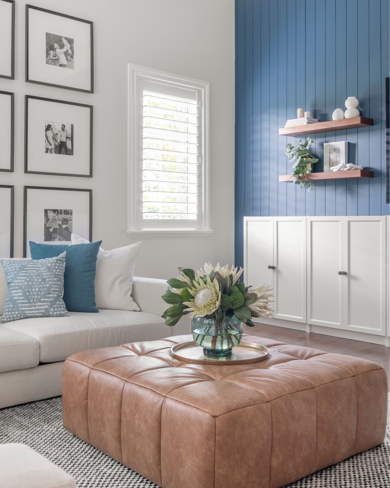 The family room, designed for comfort and practicality, features an off-white sectional treated with Scotchgard for durability and a deep blue shiplap focal wall. With upgraded IKEA bookcases for toy storage and a family portrait gallery, the space blends style and function, making it both inviting and kid-friendly. 

#LTKHome #LTKFamily
