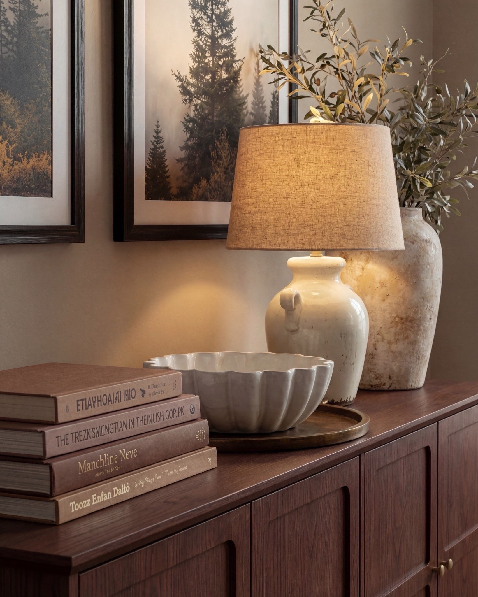 Shop the Look:
• Wood console table
• Framed landscape wall art (black frame)
• Neutral ceramic table lamp
• Stone or ceramic decorative bowl
• Large ceramic vase with faux olive branches
• Textured cube stools (neutral tone)
• Chunky knit throw blanket
• Neutral checkered patterned area rug
• White flitted decor bowl
• Brass oval serving tray
• Brown decor books

#LTKsale #LTKhome #LTKstyletip