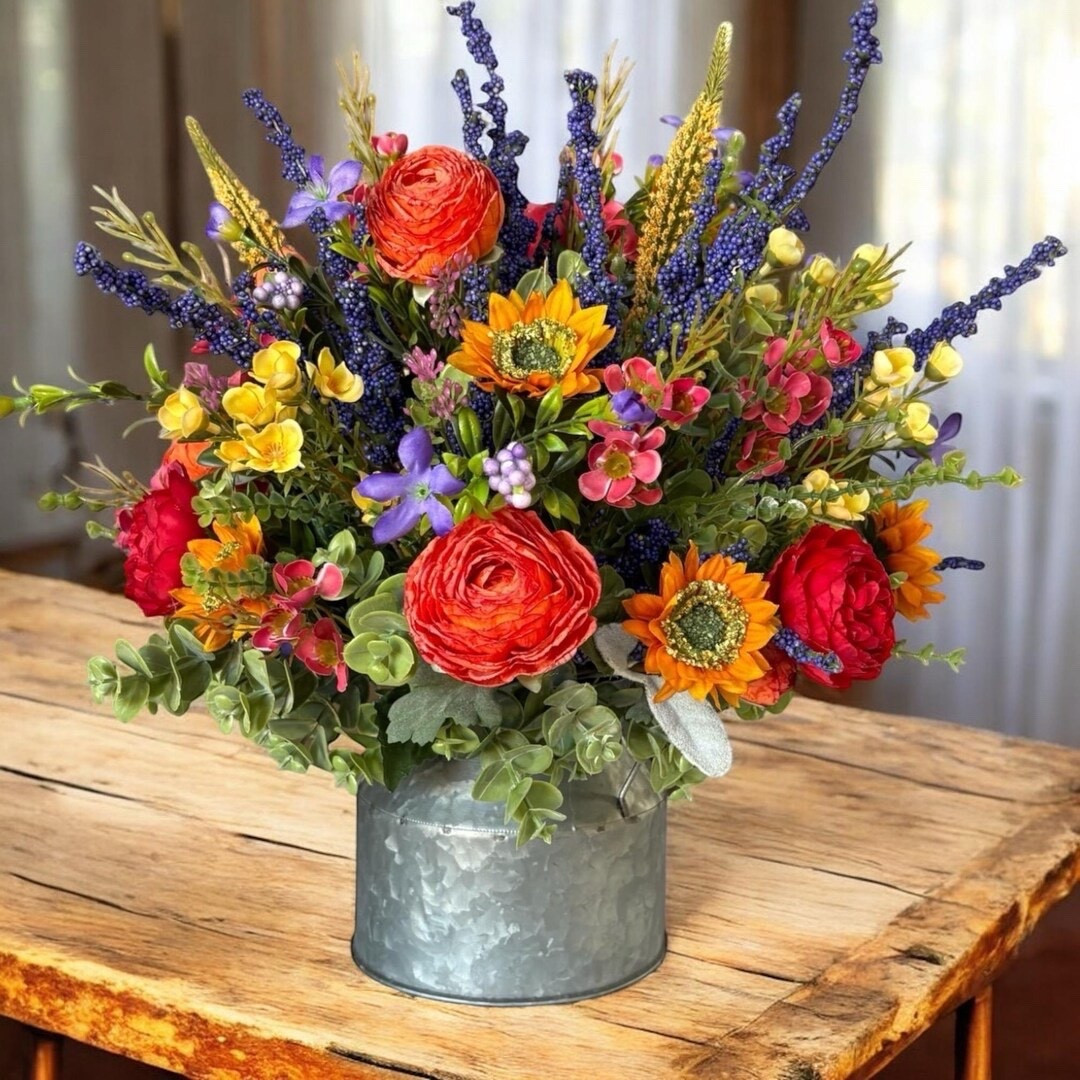 Brighten up your space with this vibrant, jewel-toned floral centerpiece bursting with color and personality. Featuring a stunning mix of mini sunflowers, peonies, roses, lavender, and delicate fillers, this arrangement is designed to look full and beautiful from every angle—perfect for your dining table or kitchen island. Accented with soft eucalyptus and moss for a natural touch, it brings bold, cheerful energy into your home without any upkeep. #LTKhome #colorfuldecor #floralcenterpiece #homedecorfinds #farmhousestyle #springvibes #tabledecor #etsyhome

#LTKHome #LTKSeasonal #LTKWedding