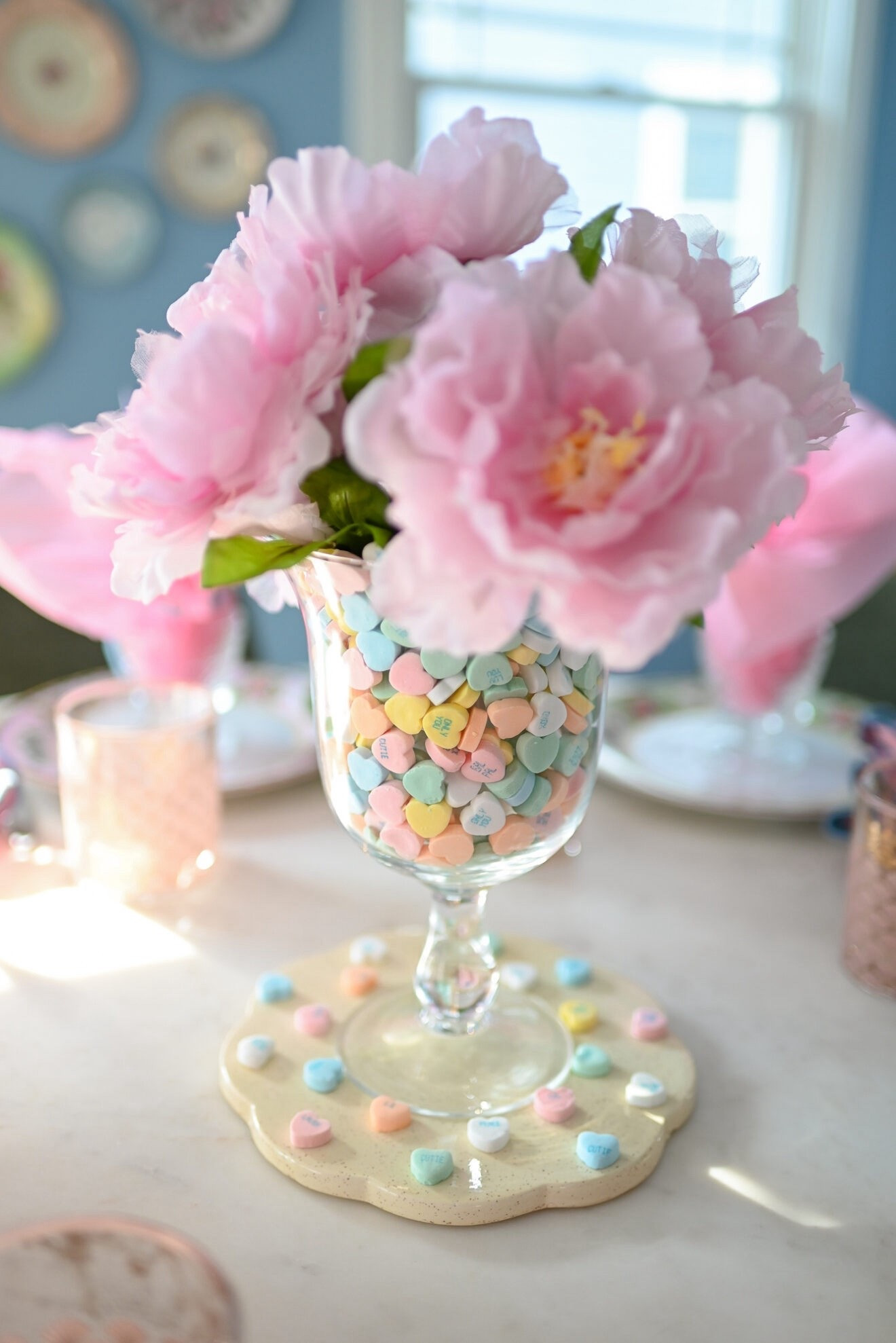 Valentine’s Day Conversation Heart Centerpiece 🩷🩵💛

For my Galentine’s Day tablescape, I knew I wanted to make a conversation heart centerpiece. I’ve had inspiration images of these saved for years, and this year I finally made it my mission to create one. I hit my local thrift store where they have an entire aisle of glassware hurricanes and vases. I selected this beautiful fluted pedestal vase and began testing out small bud vases on the surrounding shelves to stably place inside. Then you add your filler (in this case, conversation heart candy) to the space between the two vases. Though I used artificial blooms, this methods enables you to fill the smaller face with water for fresh flowers.

I also picked up this scalloped trivet to use as a jar candle plate but borrowed it for my centerpiece here first. All three items cost me $5 total. I already had these faux peonies at home in another vase. The most expensive part of the centerpiece was the candy. And if you’ve even been reticent to buy candy as vase filler because it feels like a waste, adding a small vase inside and simply filling the gap requires far less filler. The more you know!

#LTKHome #LTKValentine