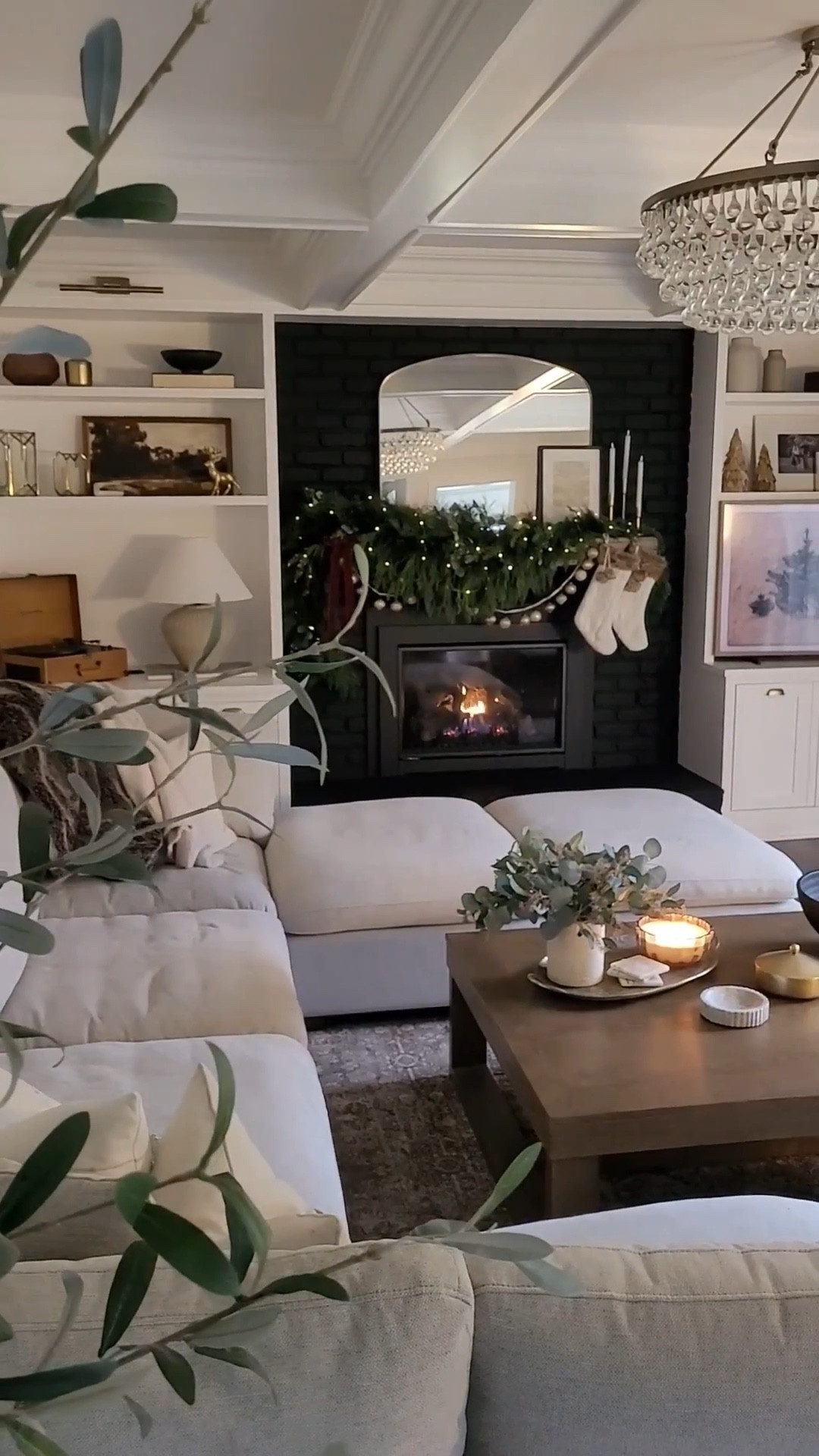 Cozy neutral vibe for our holiday family room - painting our fireplace black was such a fun decision in addition to this sectional sofa and oversized coffee table! Holiday mantle, coffee table styling, built in shelf styling, garland, neutral rug, cocktail table

#LTKHome #LTKHoliday