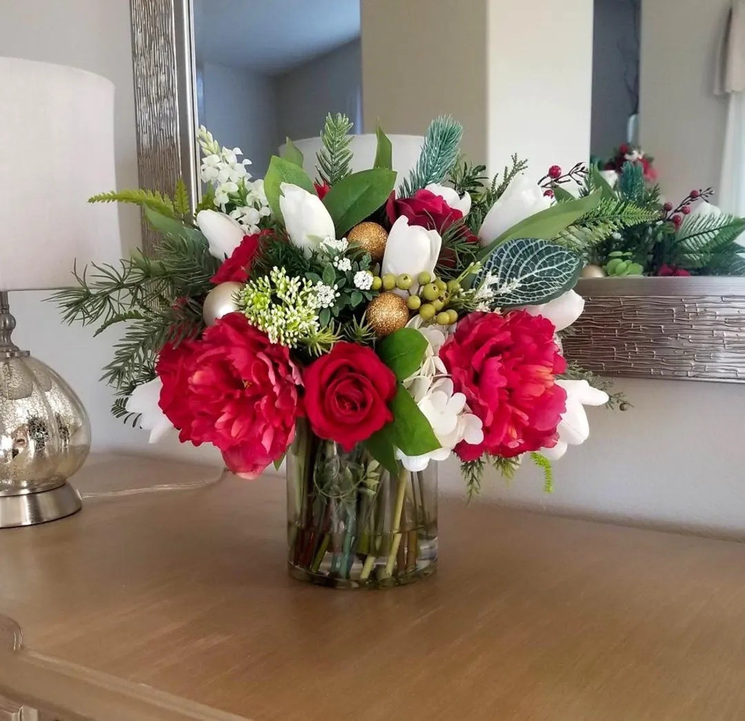 Bring effortless elegance to your holiday décor with this beautifully handcrafted Real Touch floral arrangement. Featuring lifelike roses, tulips, peonies, and Christmas greenery set in crystal-clear acrylic “water,” each piece is designed to look fresh-cut while lasting season after season. The glass cylinder adds a clean, modern touch, making it perfect for mantels, entryways, dining tables, or gifting. With incredibly realistic Floramatique® blooms, this arrangement brings festive beauty to any space—no maintenance required. ✨🌹🎄
#LTKhome #holidaydecor #realtouchflowers #christmascenterpiece #fauxflorals #etsyfinds #winterdecor #homestyling

#LTKHoliday #LTKHome #LTKSeasonal