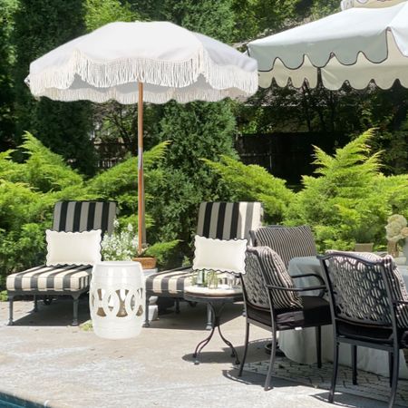 Outdoor living ideas and inspo, chaise lounge chairs, scalloped outdoor pillows, white fringe patio umbrella, black and white stripe cushions, patio umbrella, ceramic garden stool 

#LTKSeasonal #LTKfamily #LTKhome