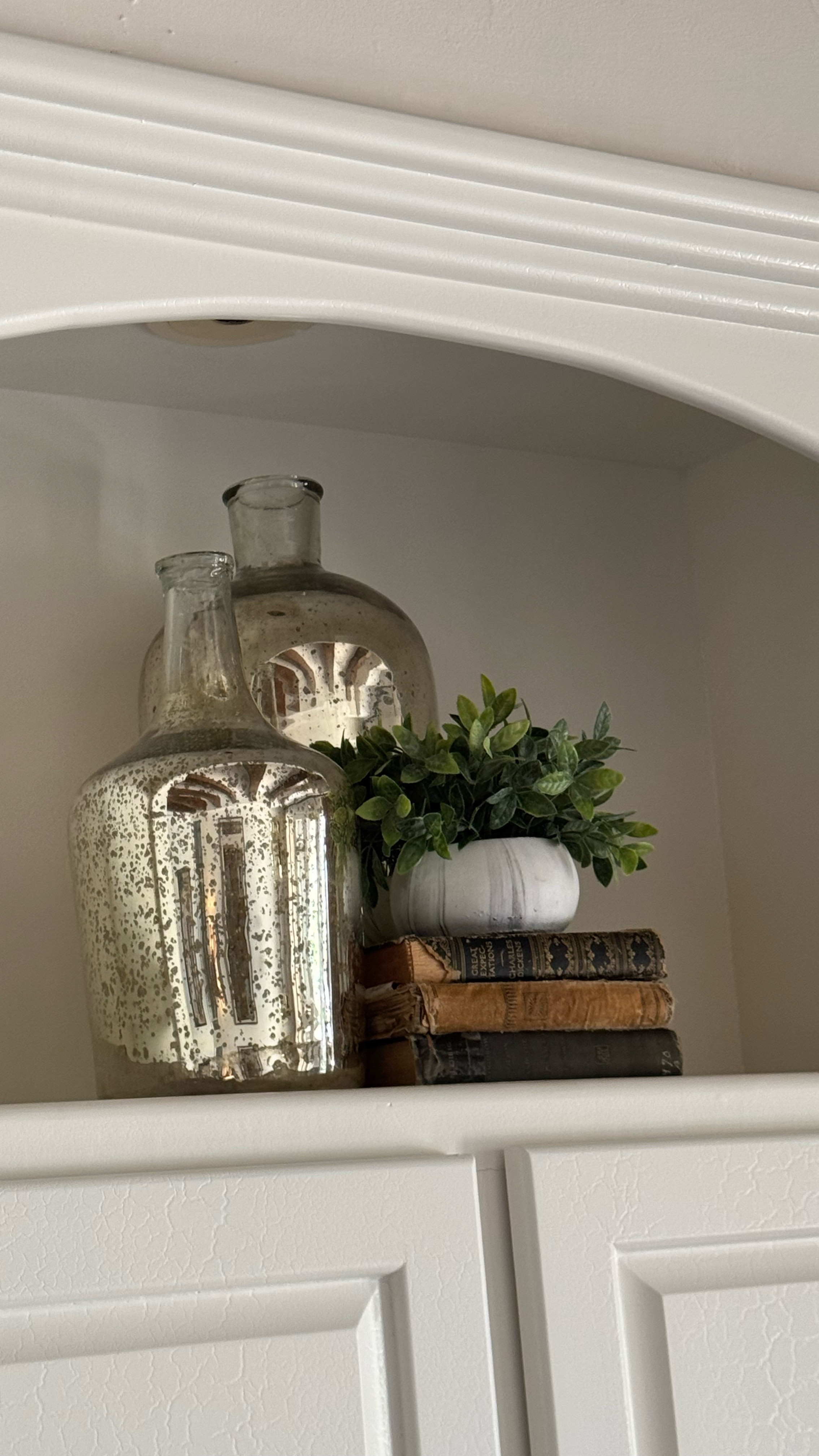 Master bedroom cabinet displays.
Liquid silver glass jars. Faux plant 
Antique books
Spiral sphere, leather box

#LTKStyleTip #LTKFindsUnder100 #LTKHome