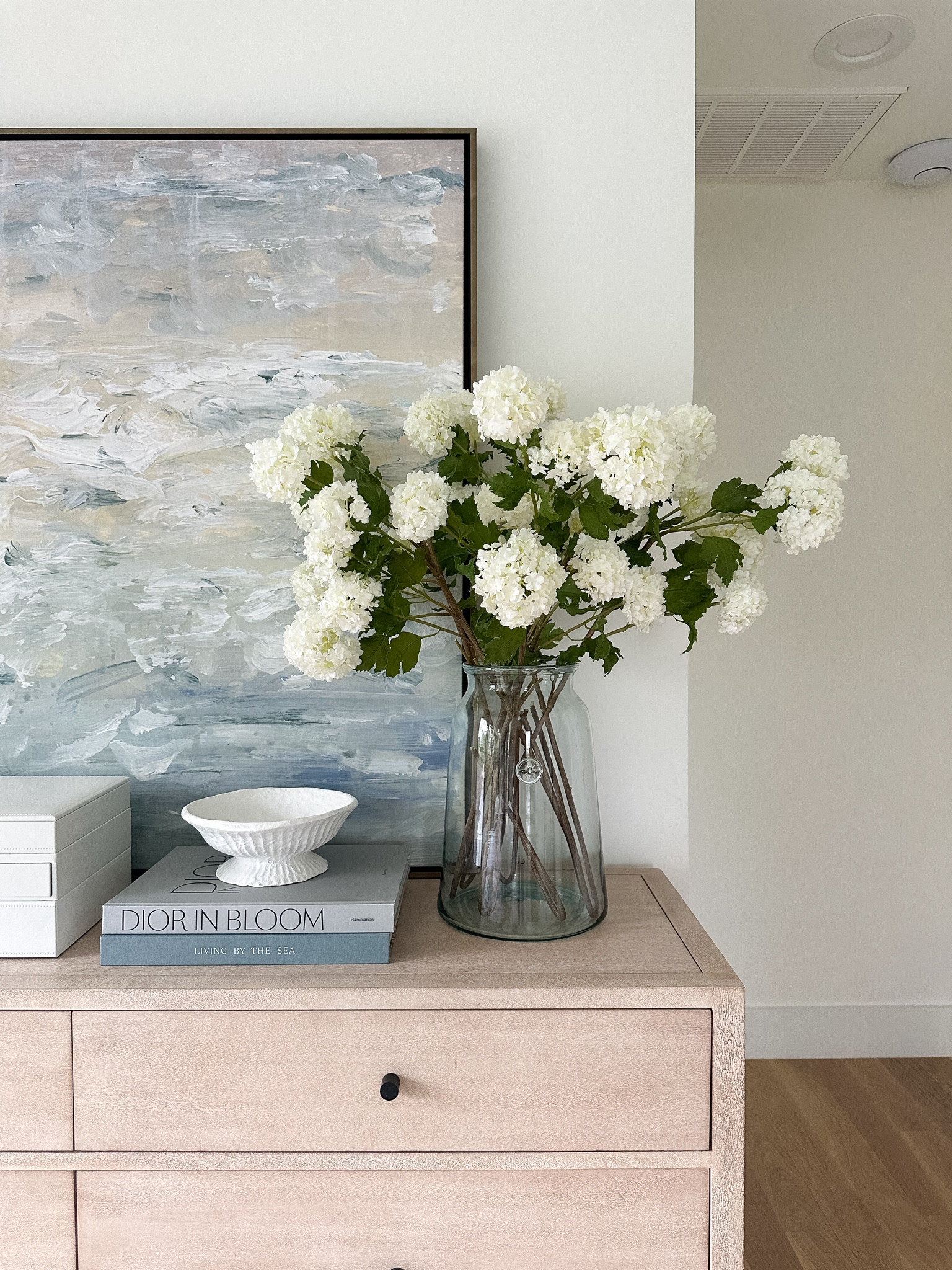 Light wood 6 drawer dresser, pottery barn, bedroom furniture, dresser styling, coastal artwork, gold lamp, faux snowball flowers, jewelry box, jewelry organizer.

Art is the 40x50” size with gallery aged brass frame 

#LTKHome #LTKFindsUnder100 #LTKStyleTip