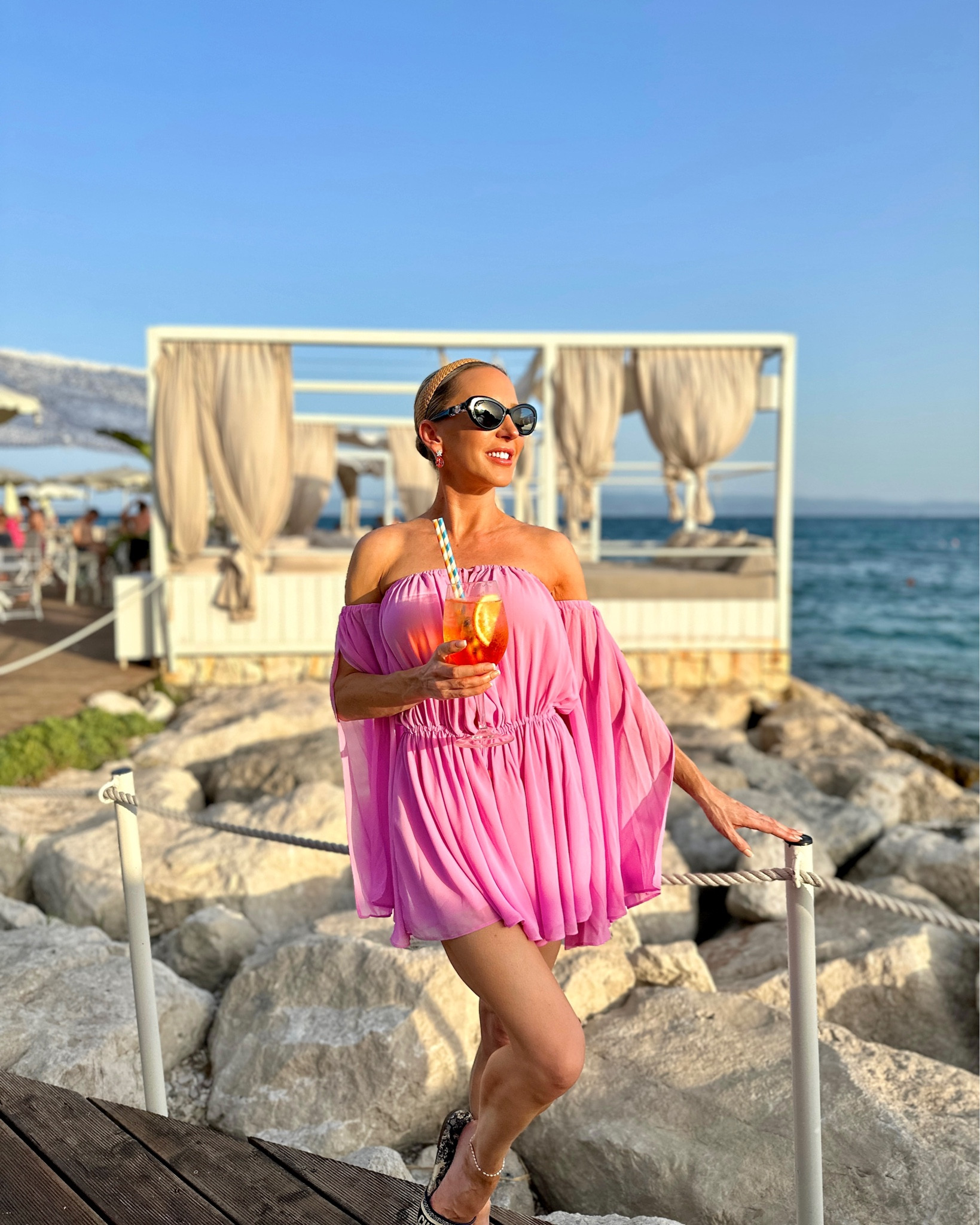 There’s always time for a Spritz 🍹 Long sleeve off the shoulder pink romper is the prettiest shade of pink and so comfy and flowy. It’s pretty plunging at the front so perfect either over a bikini or for a sexier vacation cocktail outfit. Navy Dior flat slide sandals and Chanel sunglasses on repeat.

#LTKtravel #LTKFind #LTKSeasonal