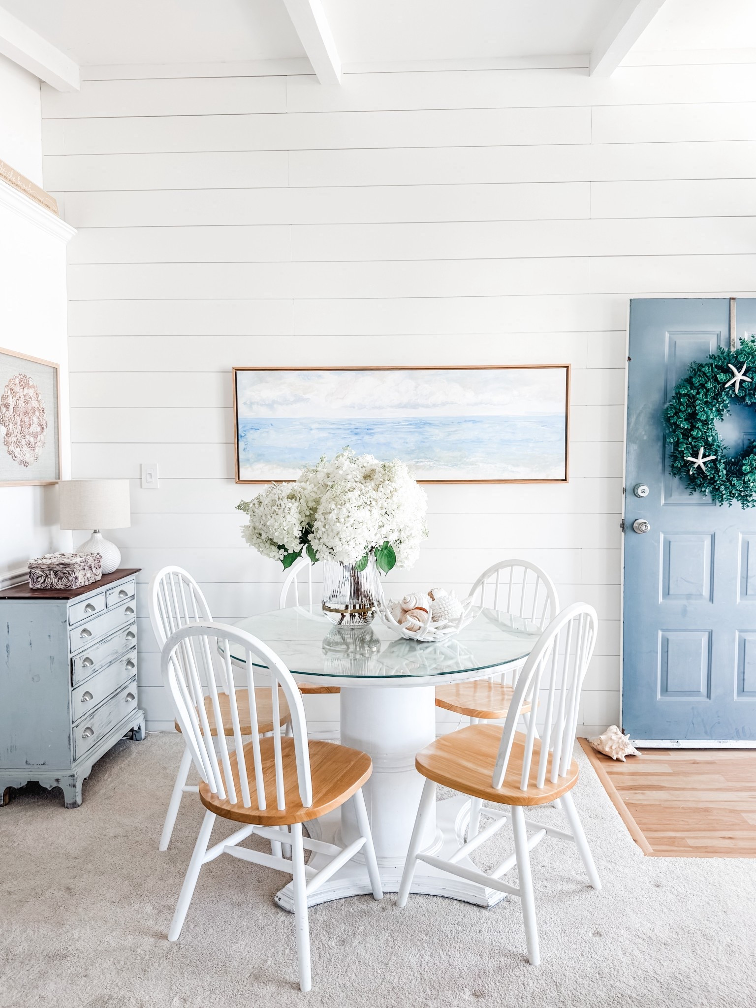 Coastal decor
White farmhouse wood spindle Windsor dining chairs
Textured ceramic table lamp
Crystal Tide coastal wall art by Lindsay Letters
Panoramic wall art
Coastal wall art
Artificial shell decor
Beach house decor 