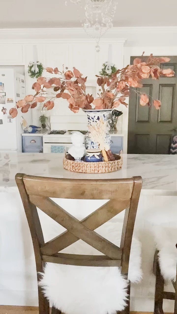 Bring a touch of autumn charm to your home with this simple, layered Thanksgiving kitchen island centerpiece. ⁣
⁣
I started with a small white bust sculpture — it adds a hint of personality and a touch of European flair without feeling too formal. Then I placed a blue and white vase filled with tall, 36" fall eucalyptus stems. The height draws the eye up and makes the whole vignette feel balanced and elegant.⁣
⁣
To ground the look, I added a mini corn husk bundle for texture and a blue and white pumpkin to tie in those soft harvest tones. A single candle warms up the mix, making it glow beautifully in the evenings without overwhelming the space.⁣
⁣
This setup works perfectly for your kitchen island, dining table, or entry console — anywhere you want a cozy fall moment without crowding the surface. The mix of natural textures, warm light, and layered heights keeps it feeling intentional but effortless.⁣
⁣
💡 𝐒𝐭𝐲𝐥𝐢𝐧𝐠 𝐭𝐢𝐩: Use odd numbers (3 or 5 items) for balance, and mix contrasting materials — ceramic, natural fiber, and candlelight — for that collected, designer look.⁣
⁣
Keep this look going from September through Thanksgiving by swapping in fresh greenery or an extra candle as the season shifts.⁣
⁣
Follow @julie_ann_rachelle for more cozy, attainable home styling ideas all season long.⁣
⁣
#fallhome #autumndecor #thanksgivingdecor #blueandwhite #cozyhome #falldecorideas #kitchenislanddecor #centerpieceideas #harvestdecor #traditionalhome #LTKHome #LTKHoliday #LTKStyleTip 

 #LTKSeasonal #LTKHome #LTKFindsUnder50