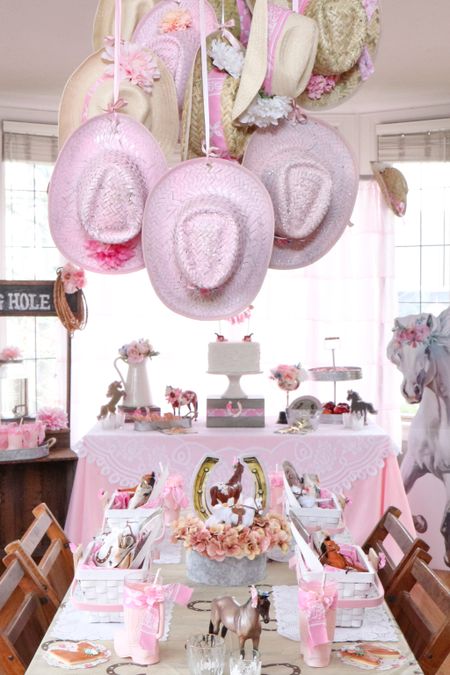 This DIY cowgirl hat chandelier is perfect for a Rustic Horse party. Simply paint some hats with pink spray paint, add pink flowers and handkerchiefs to others, and hang from the ceiling with pink ribbon and faux florals!

#cowgirlparty #horseparty #kidsparty #birthdayparty #partyideas #diypartydecor

#LTKhome #LTKparties #LTKkids