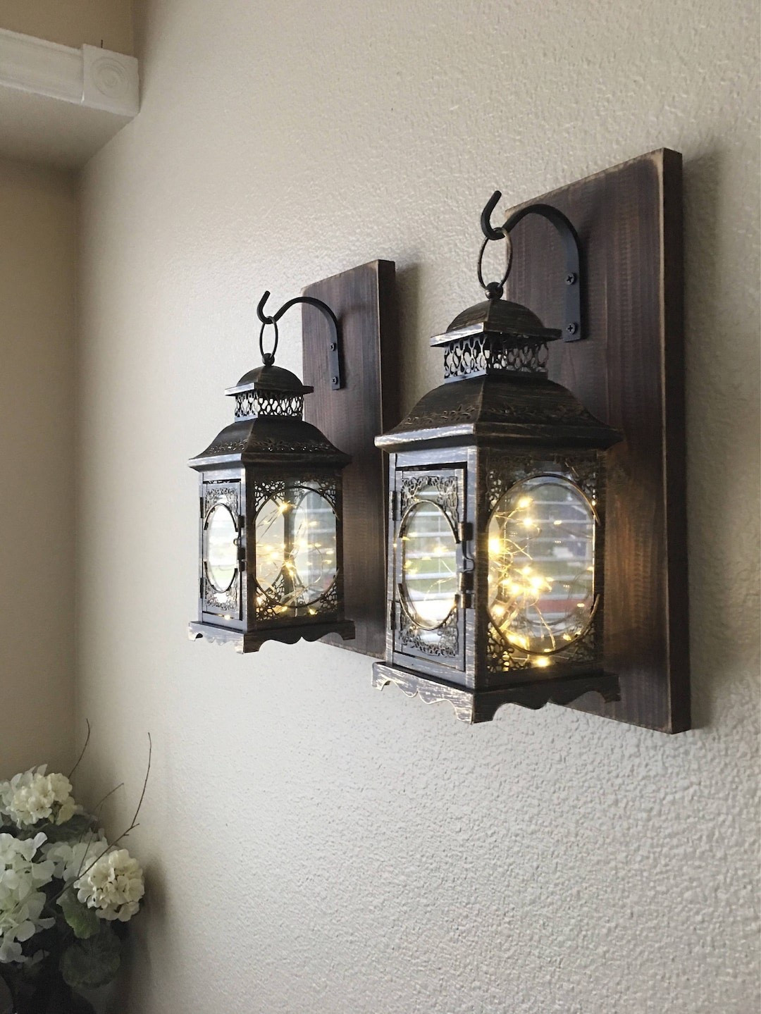Add a warm, inviting glow to your space with these farmhouse lantern sconces by CountryHomeandHeart. Featuring beautifully distressed black and bronze lanterns mounted on customizable wood backings, this set brings the perfect blend of rustic charm and classic elegance. Whether styled in an entryway, living room, or bedroom, these sconces create a cozy ambiance while adding depth and character to your walls. #LTKHome #FarmhouseDecor #WallSconces #RusticStyle #CozyLighting #HomeStyling #NeutralHome #WarmAndInviting

#LTKHome #LTKSeasonal