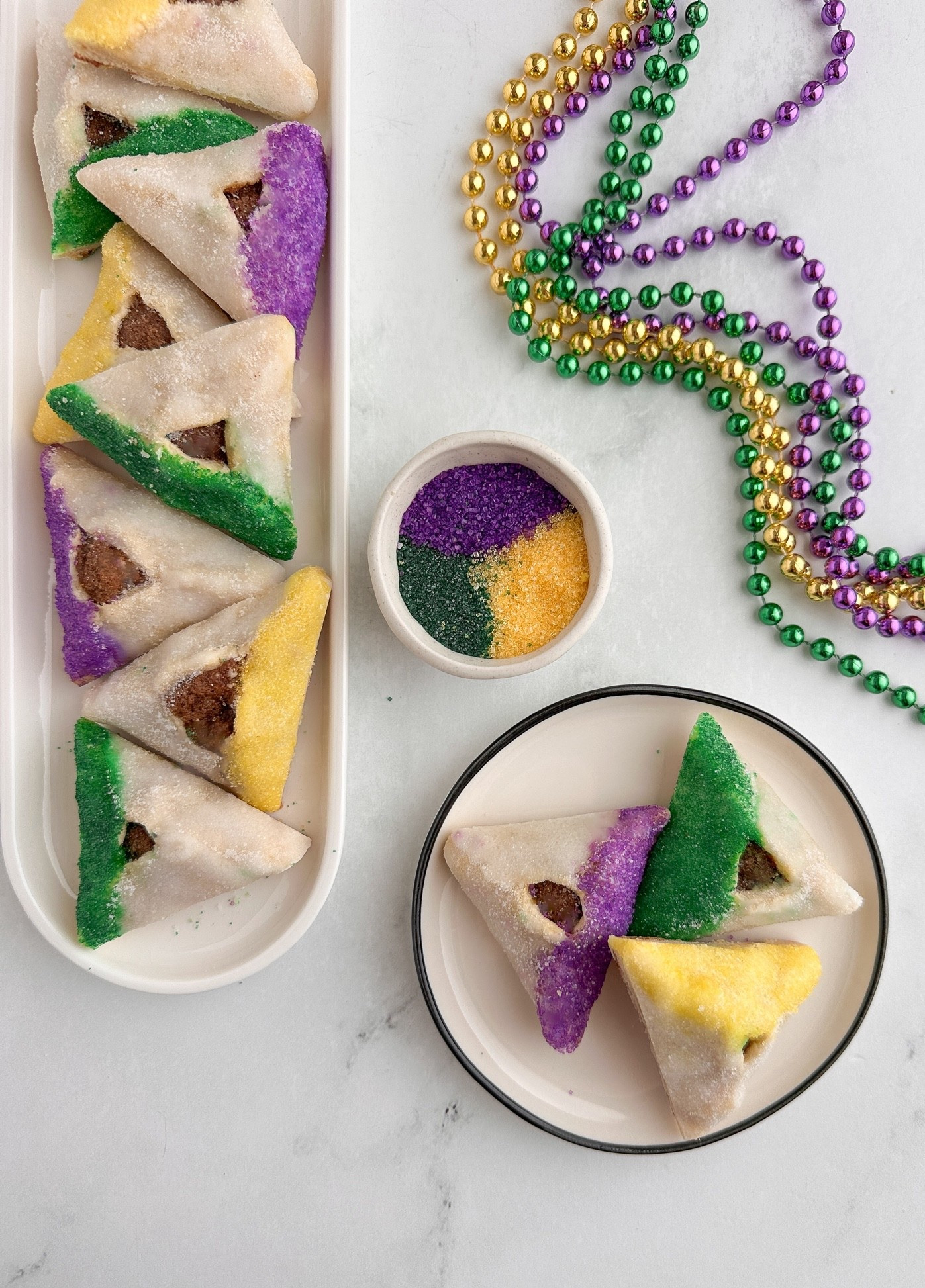King Cake Hamantaschen My annual hamantaschen riff gets a Mardi Gras spin - cinnamon brown sugar
filling, vanilla glaze, and purple, green and gold sanding sugars. The rolling pin spacer bands are the key to getting that 1/4-inch thickness every time. Everything is linked here. Full recipe at sherisilver.com

#LTKHome #LTKSeasonal #LTKfoodie